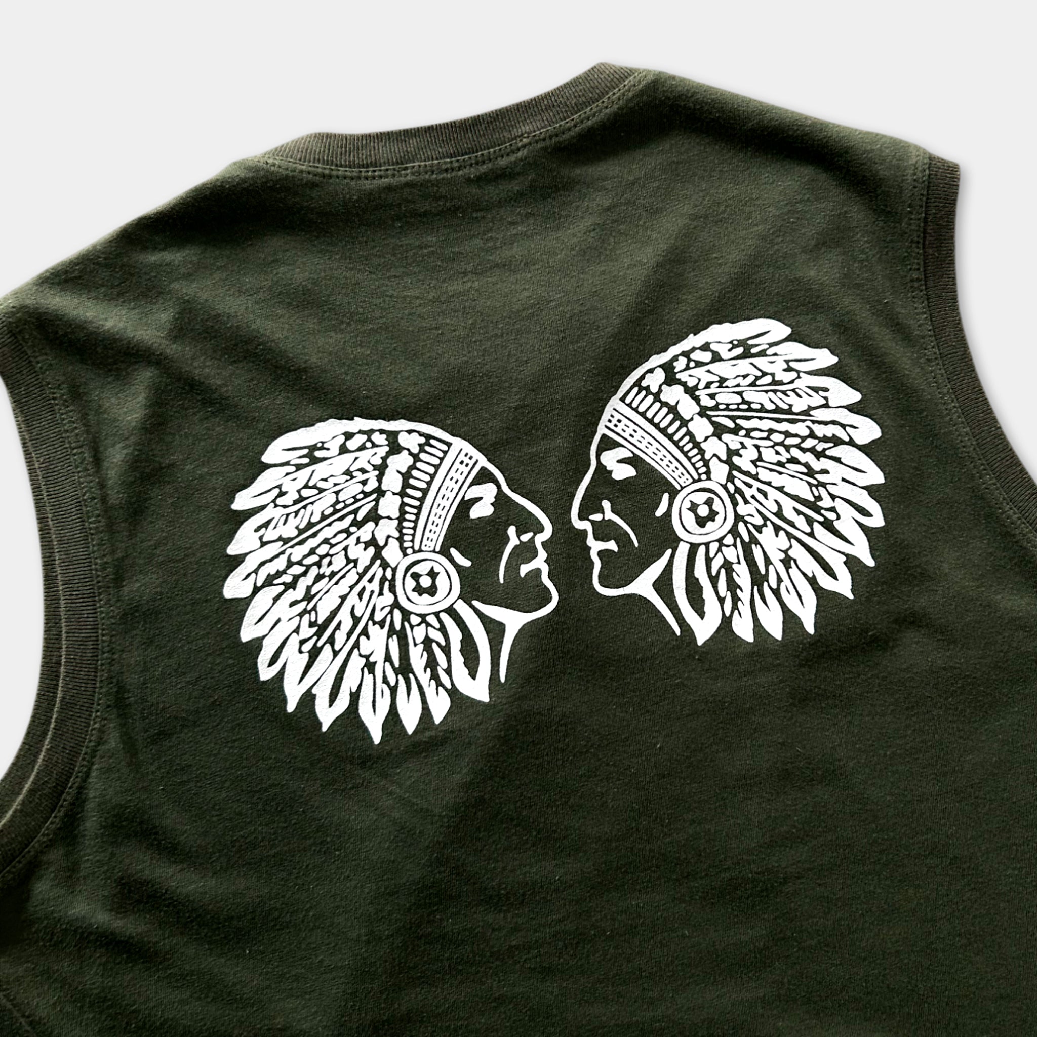 a dark green sleeveless t-shirt with a white graphic design on the back, depicting two Native American heads facing each other.