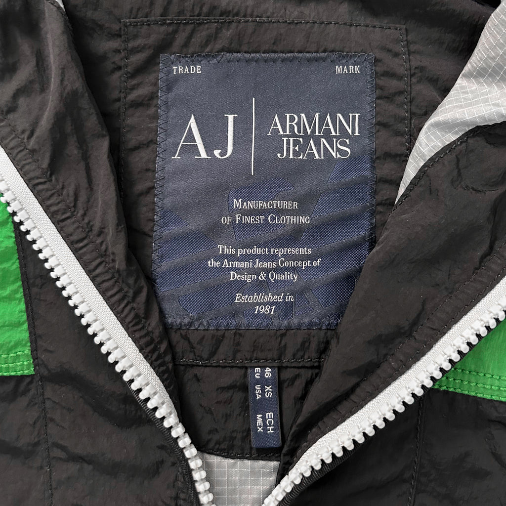 a close-up view of a black and green jacket with a zipper, featuring a label that displays the brand name and product information.