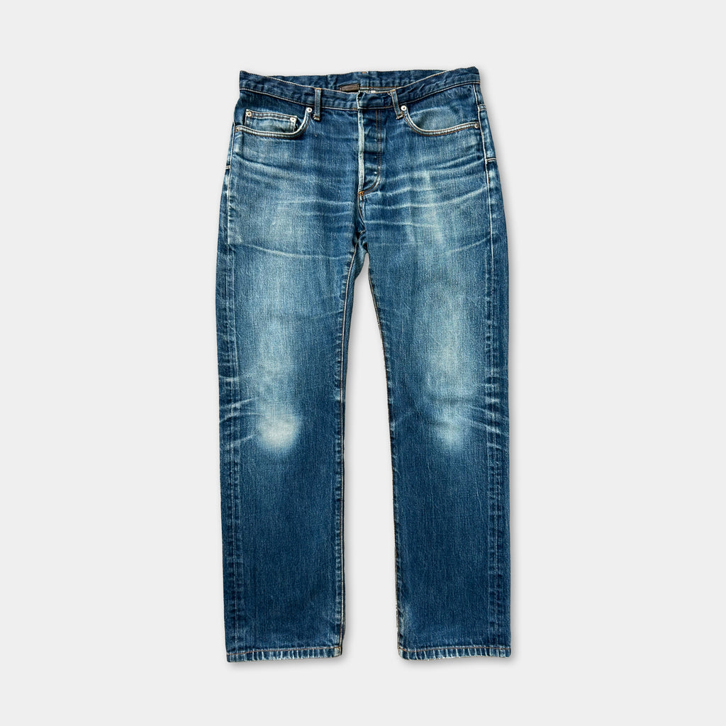 A pair of blue jeans with visible signs of wear and tear, including faded blue denim fabric and visible creases.