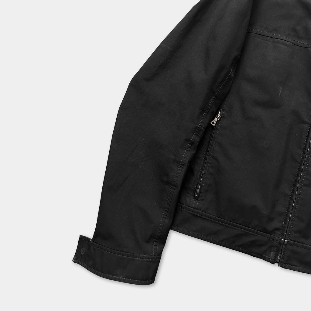 A black jacket with a zipper and pockets is shown against a white background.