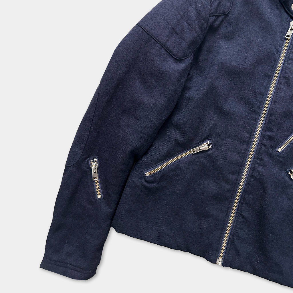 A navy blue jacket with multiple zippers and pockets, including a zipper on the left arm and a zipper on the right arm.