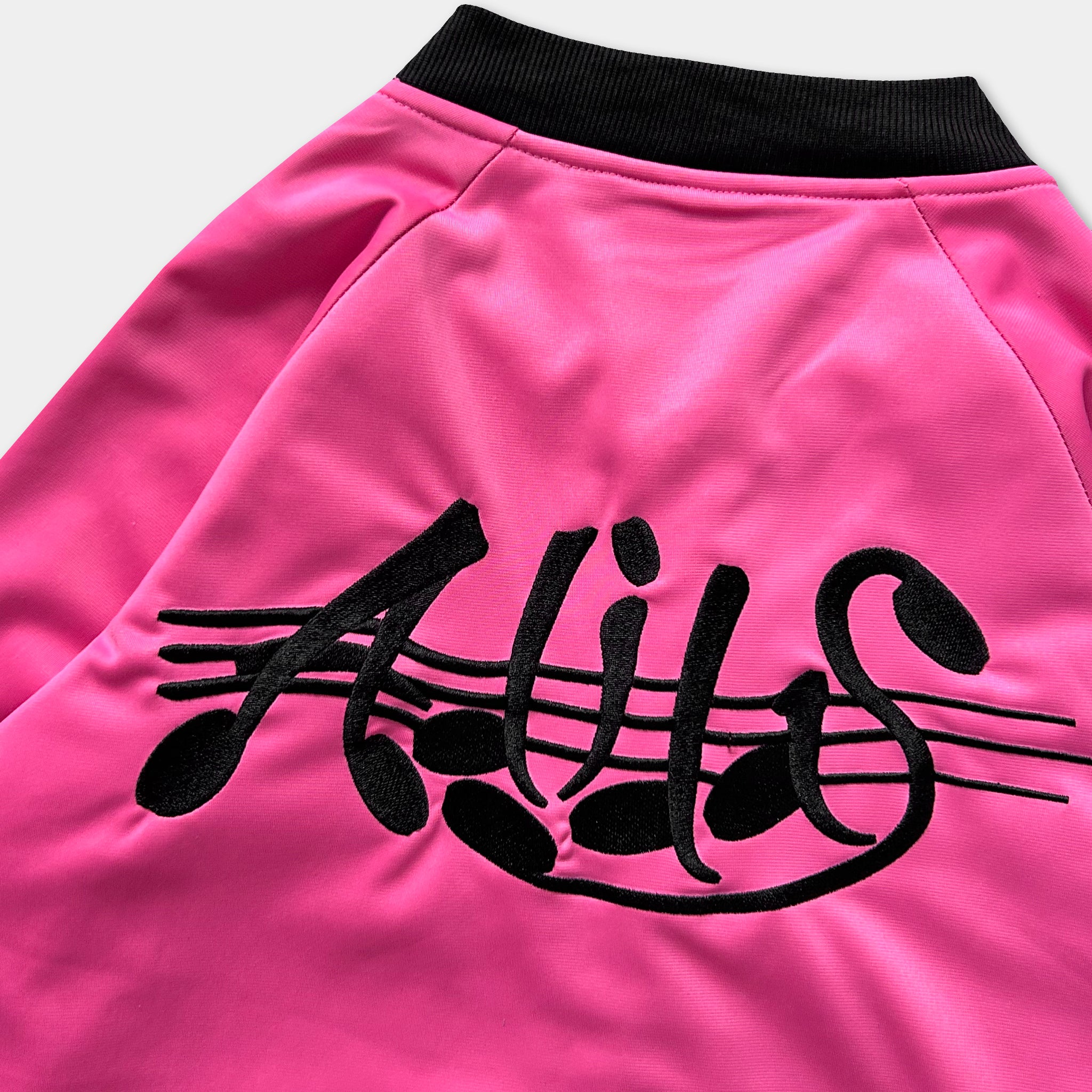 A bright pink jacket with black text and musical notes embroidered on it.