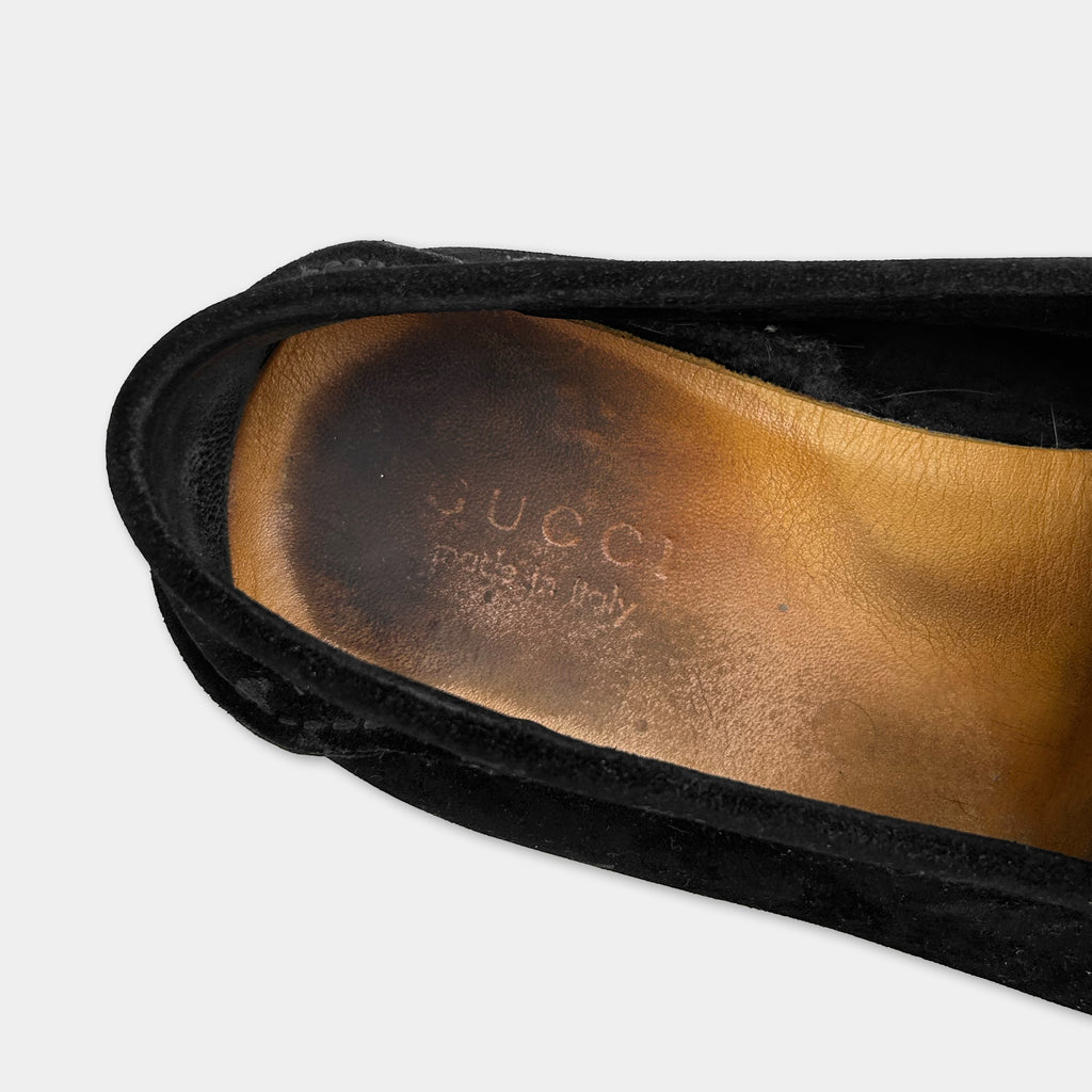 A close-up view of a black Gucci shoe, showing the brand name and the country of origin on the sole.