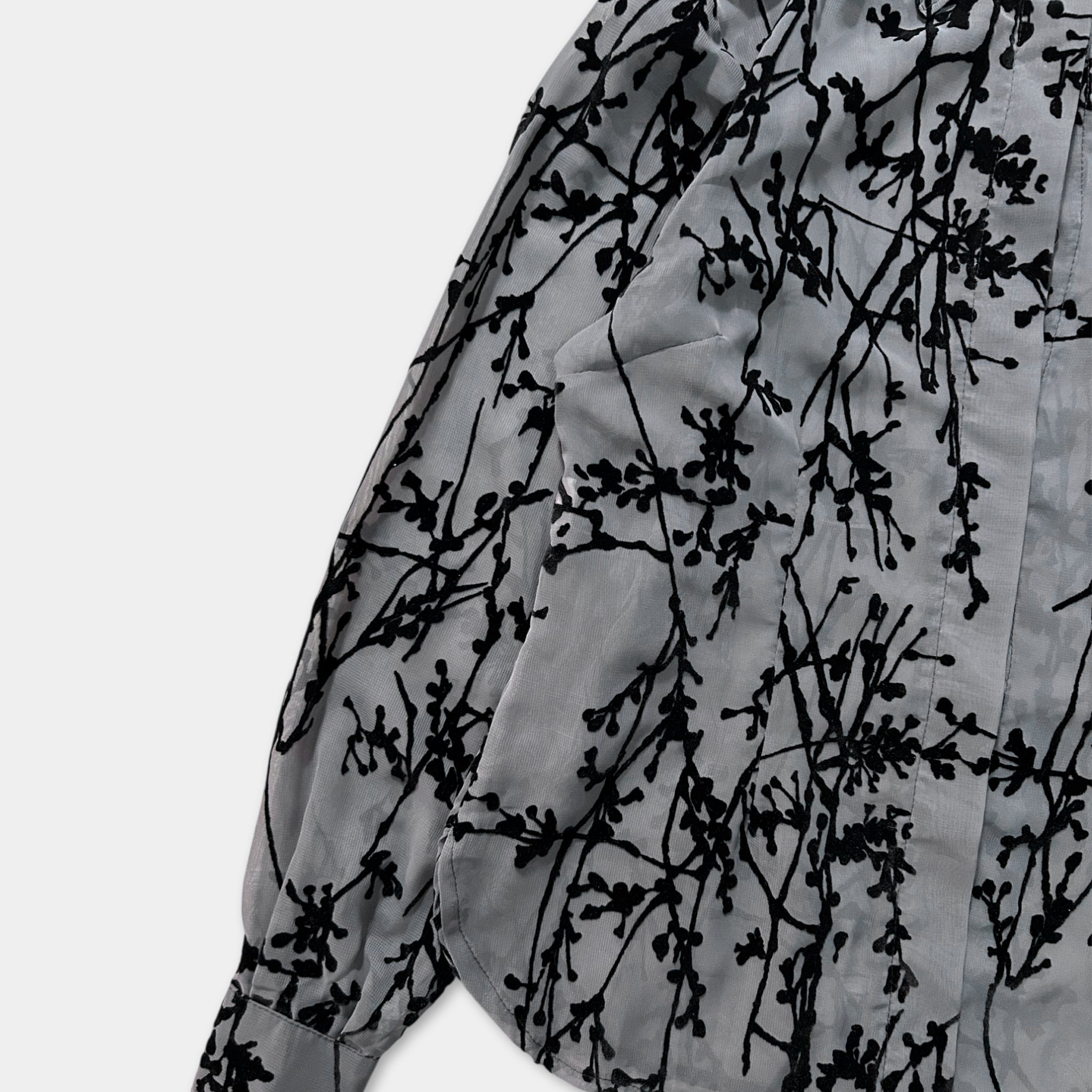 a close-up view of a gray shirt with a black floral pattern.