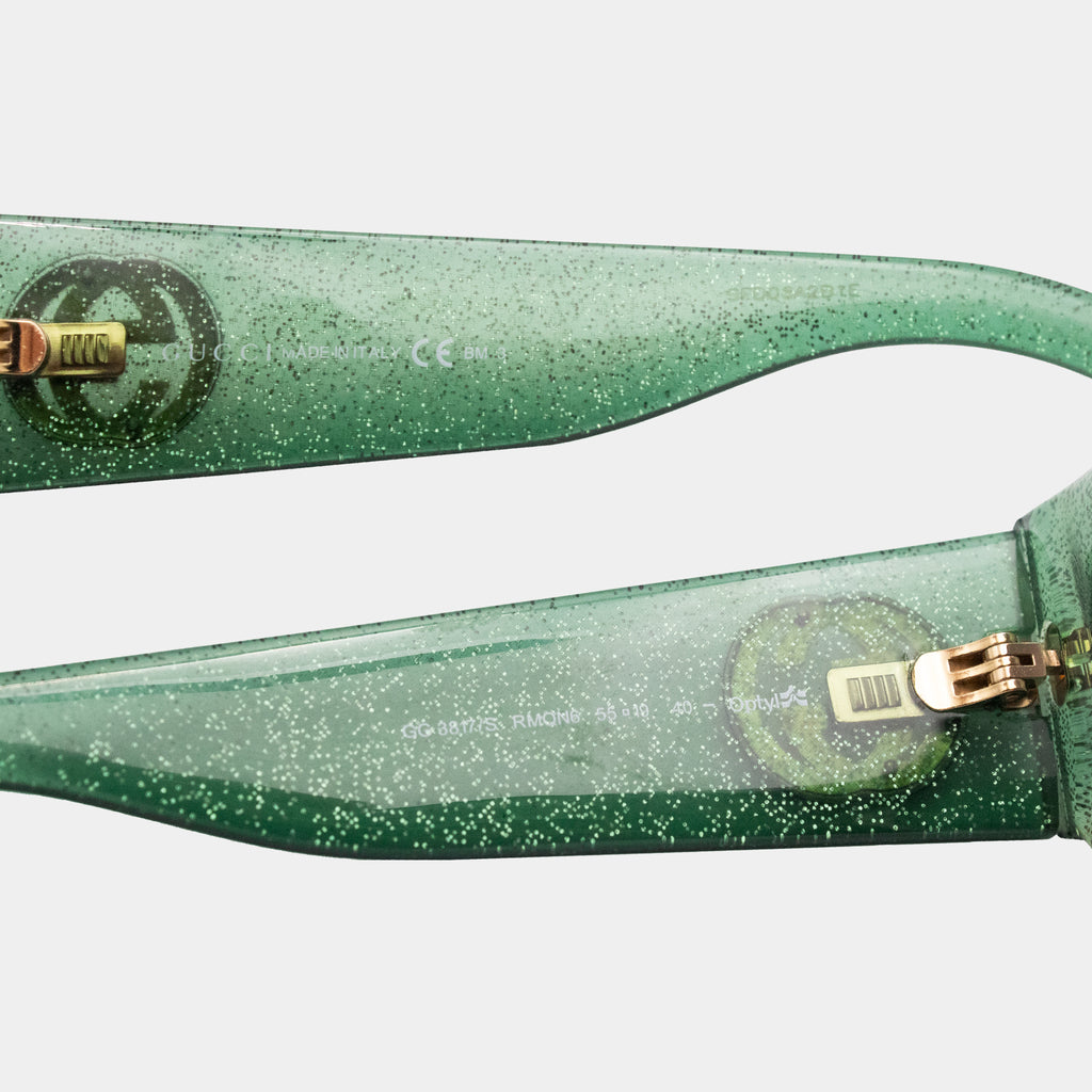 A pair of green glittery sunglasses with gold accents.