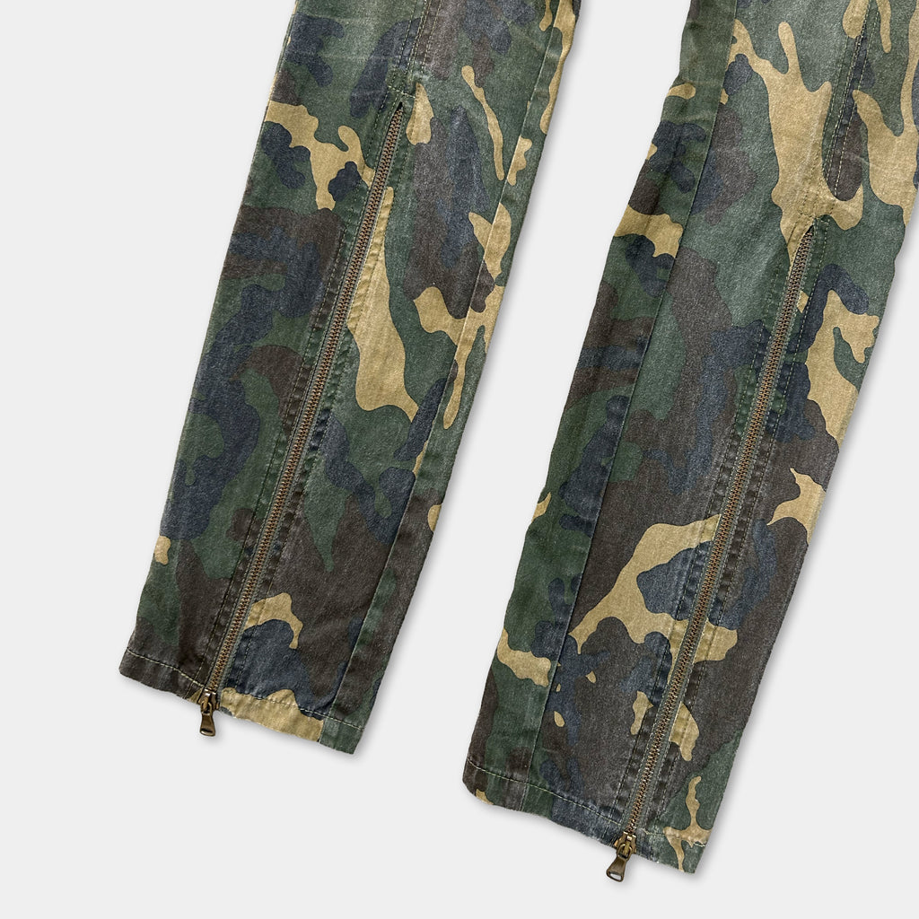 a pair of camouflage pants with zippers, featuring a distinctive pattern of green, brown, and black colors.