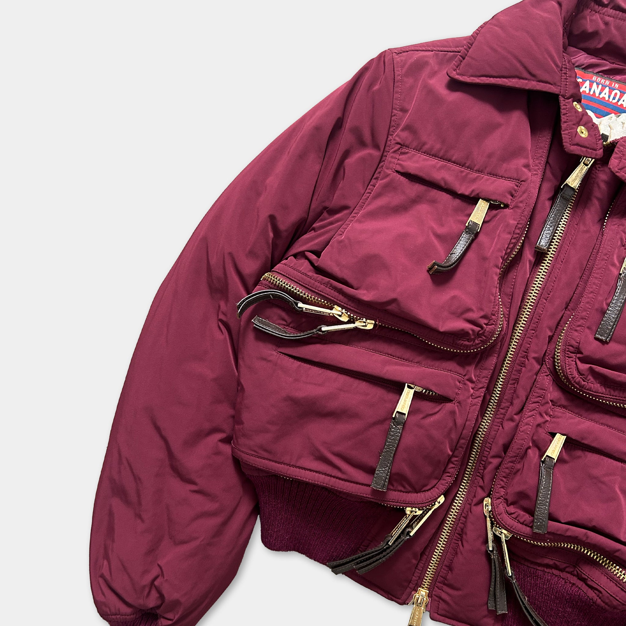A maroon jacket with multiple zippers and pockets, featuring a collar and a collar-less design.