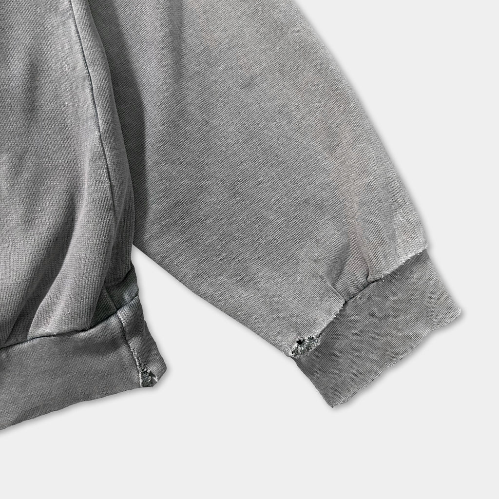 a close-up view of a grey sweatshirt sleeve with a small tear near the cuff.