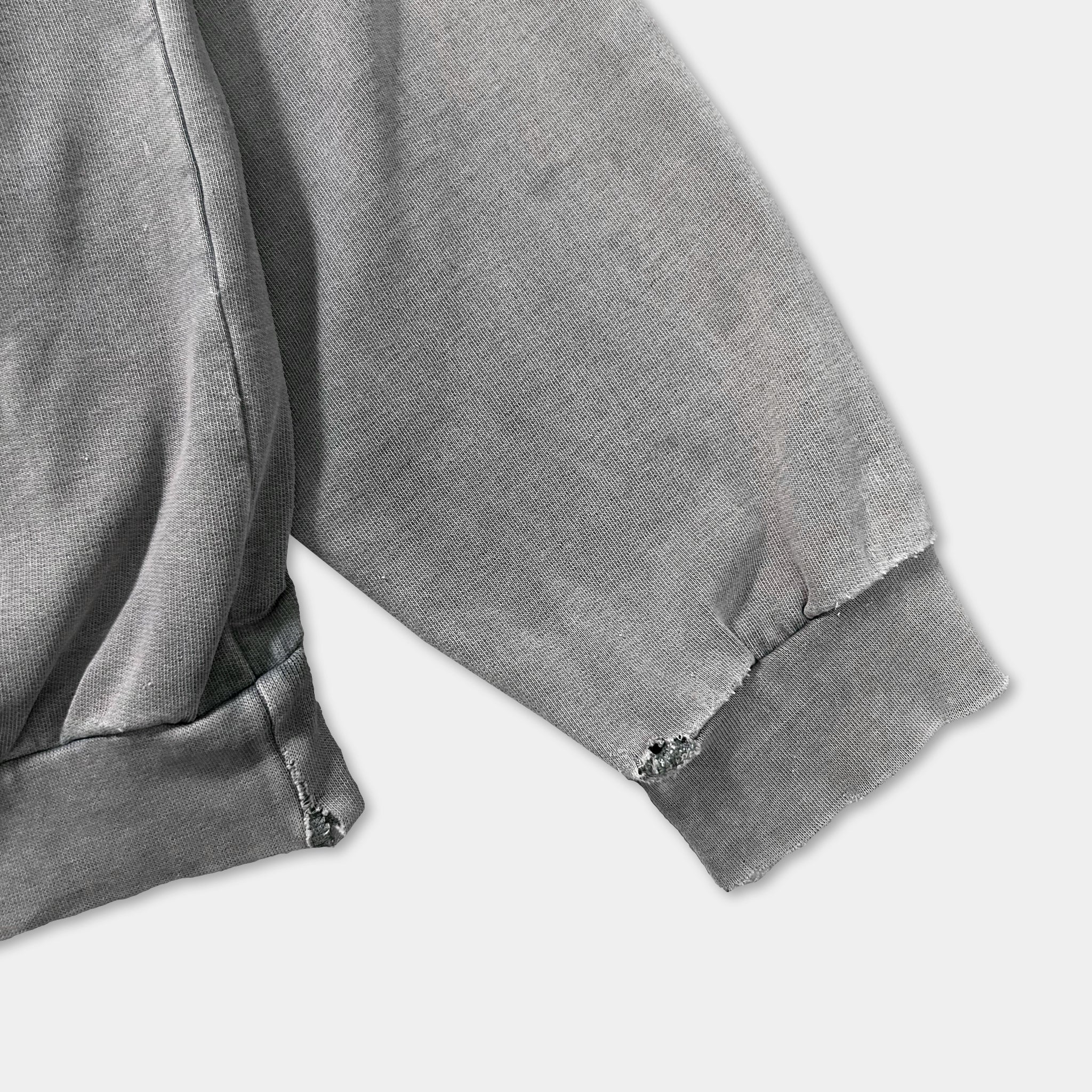 a close-up view of a grey sweatshirt sleeve with a small tear near the cuff.