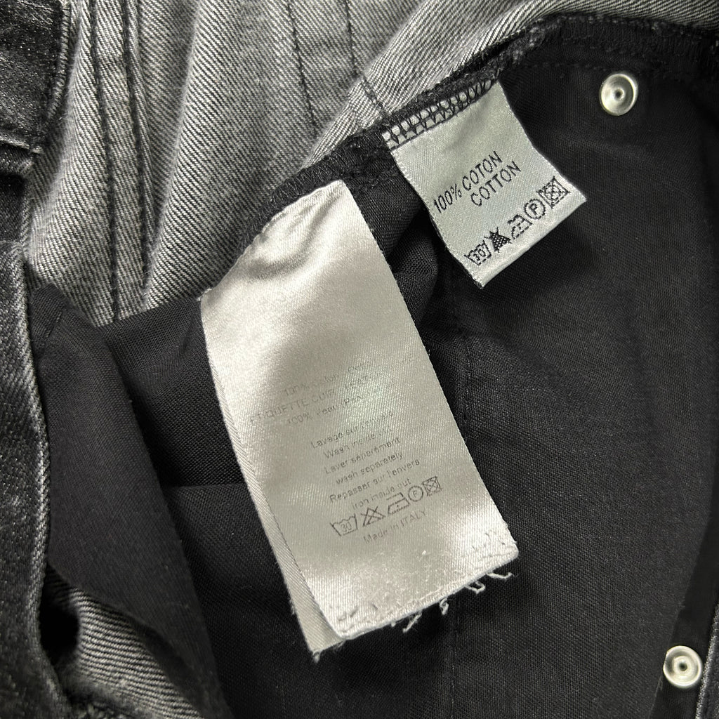 a close-up view of a garment, possibly a pair of jeans, with a label attached to it. The label appears to be a care label, indicating the garment is made of 100% cotton and has been washed in cold water.