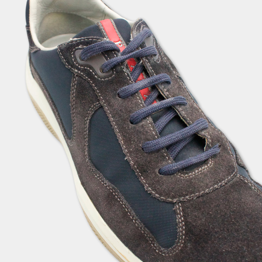 A close-up view of a dark gray and red shoe with blue laces.