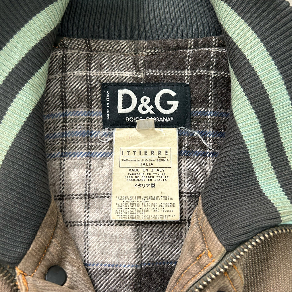 a close-up view of a D&G jacket, featuring a label on the collar and a tag hanging from the zipper.
