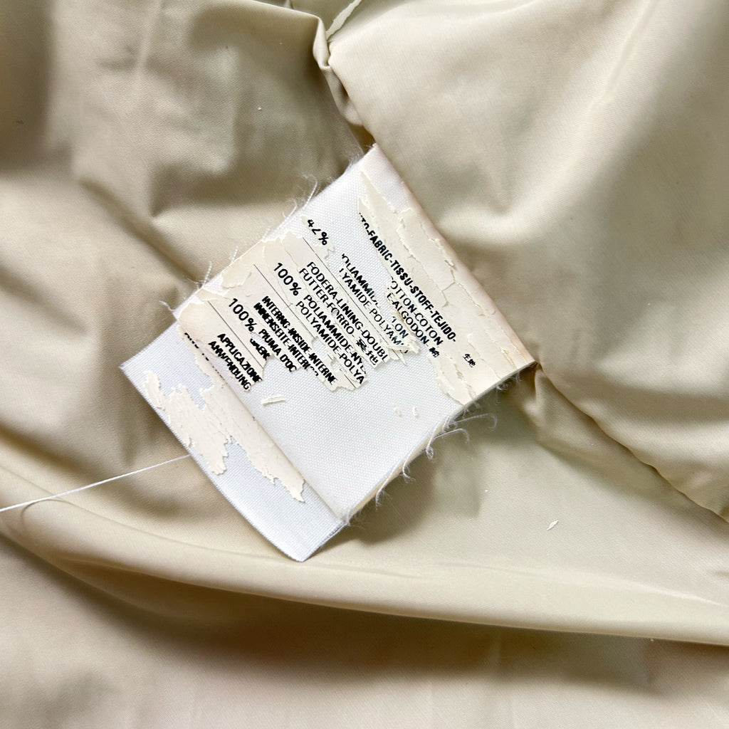 a torn label attached to a piece of fabric, with visible fabric and thread visible.