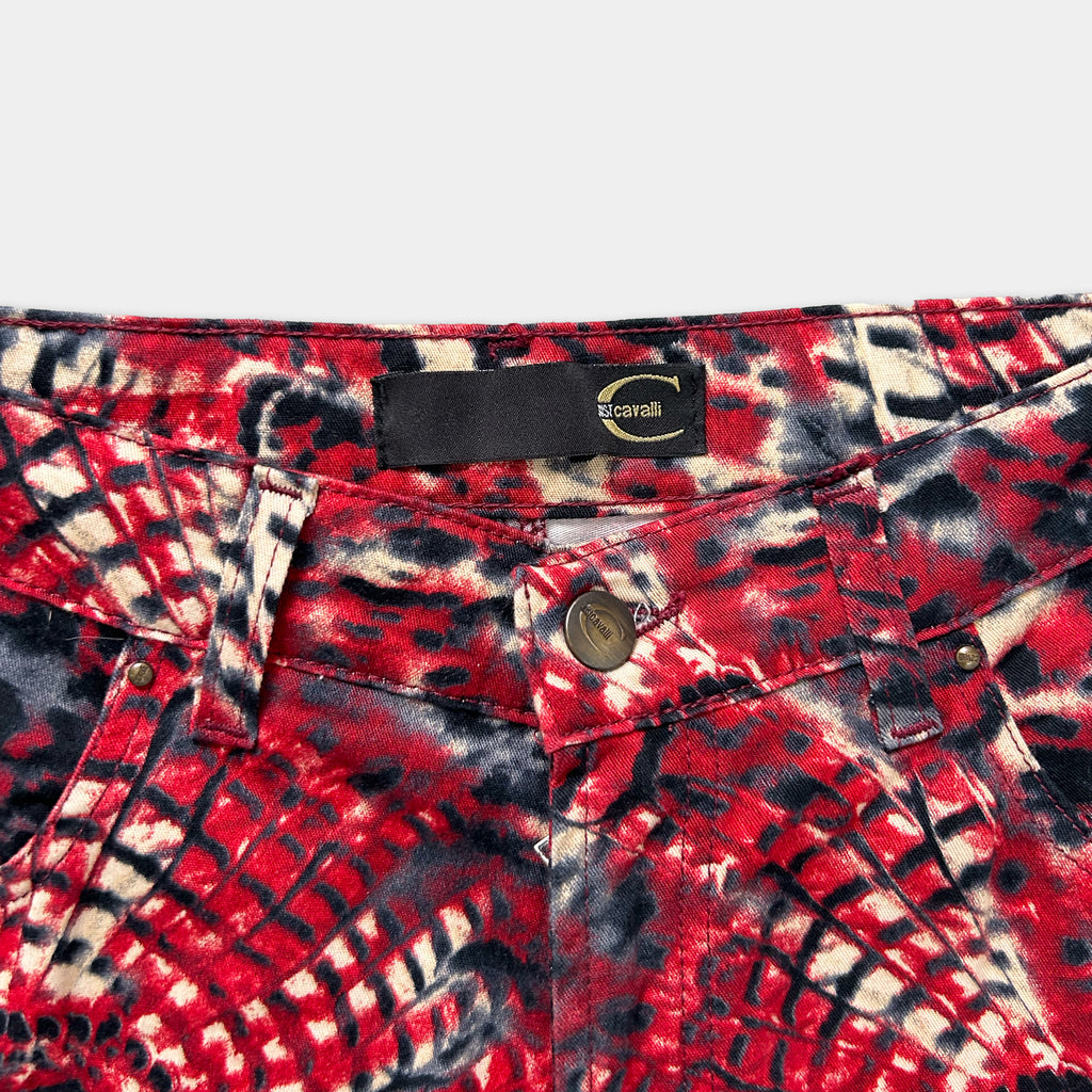 A close-up view of a pair of red and black patterned jeans, with a label on the waistband.