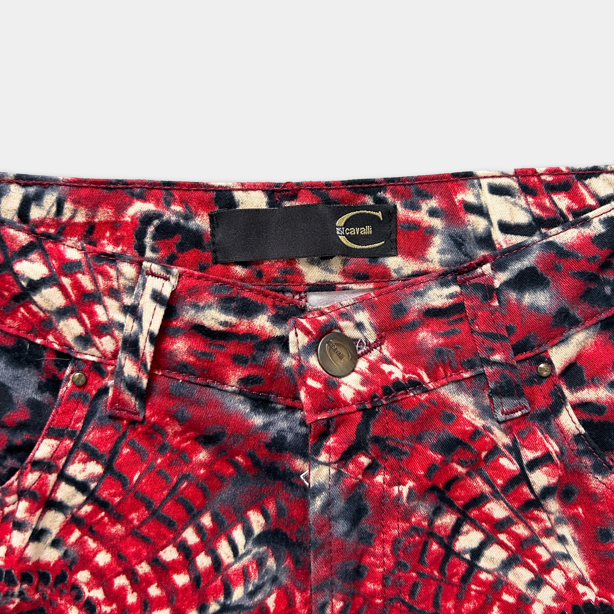 A close-up view of a pair of red and black patterned jeans, with a label on the waistband.