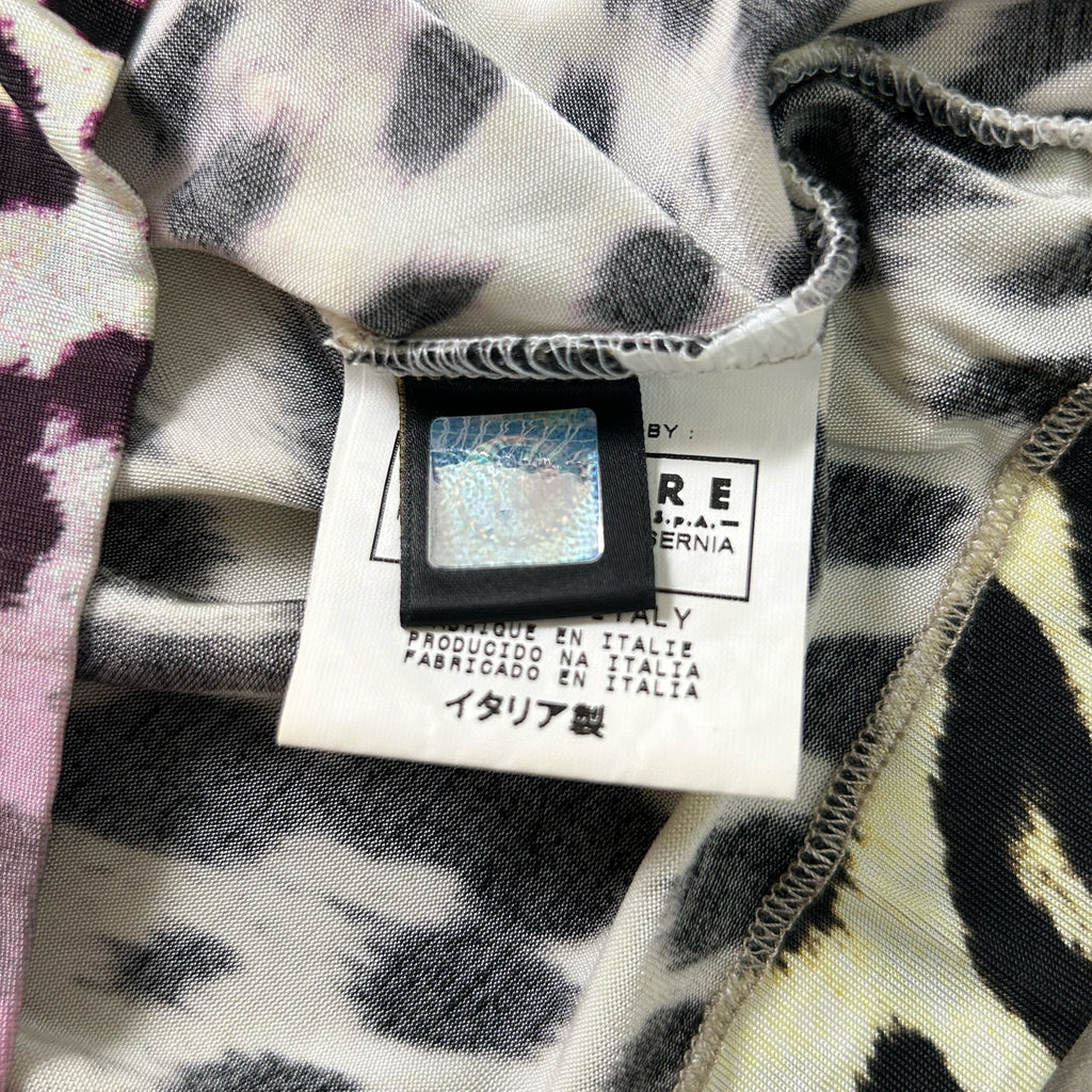 a close-up view of a fabric label with text and a barcode, attached to a piece of clothing with a leopard print pattern.