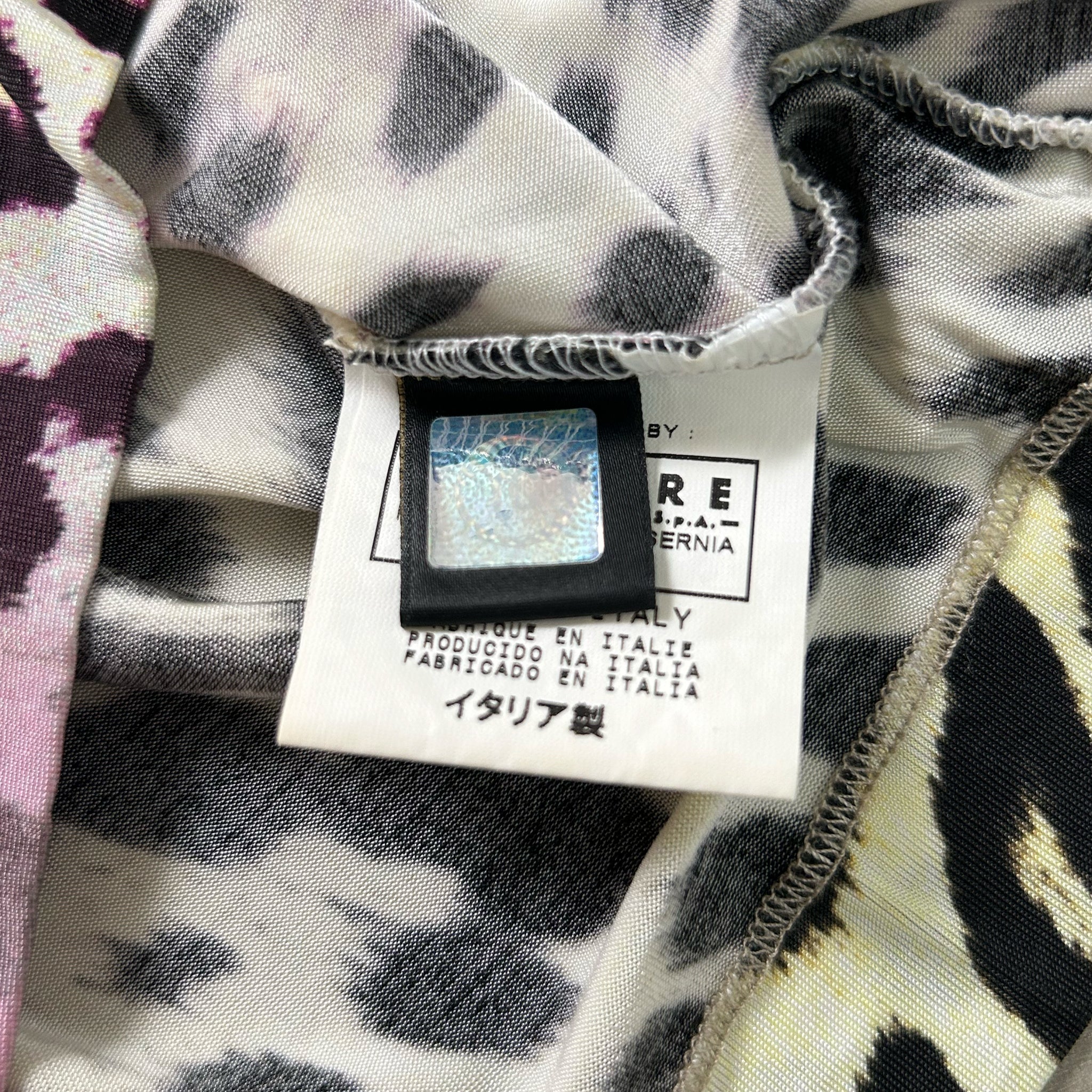 a close-up view of a fabric label with text and a barcode, attached to a piece of clothing with a leopard print pattern.