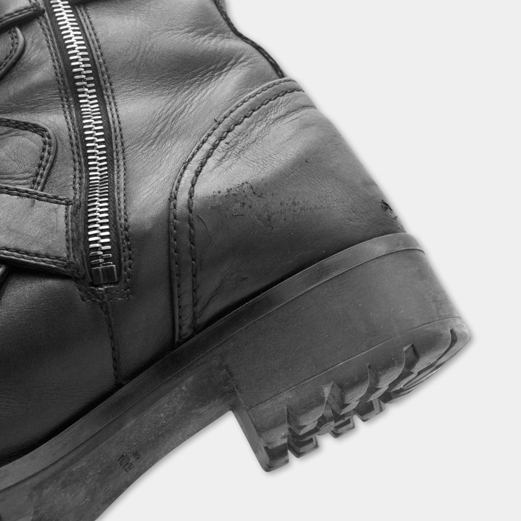 A close-up view of the side of a black leather boot with a zipper closure.