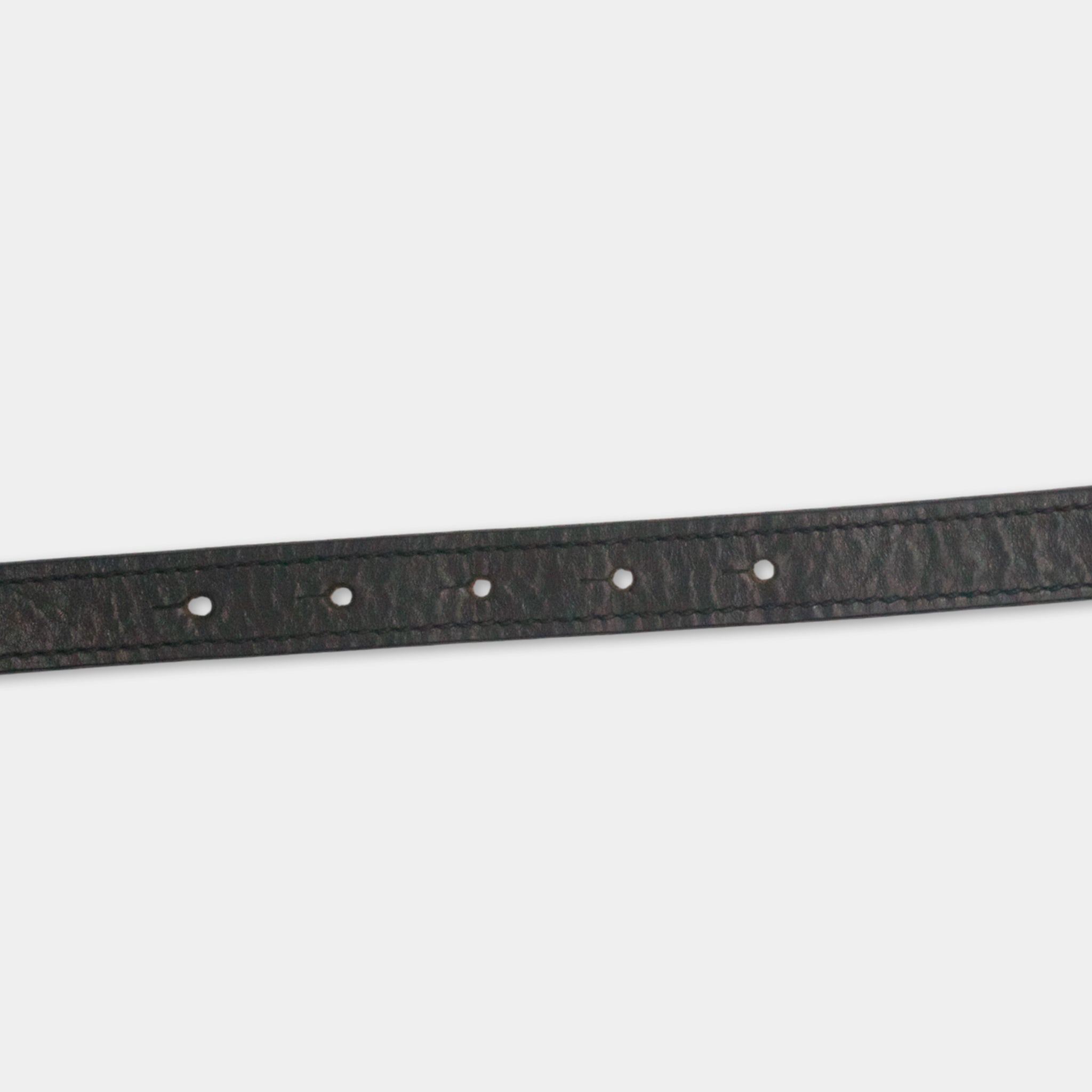 A black leather belt with a row of small holes along the top edge.
