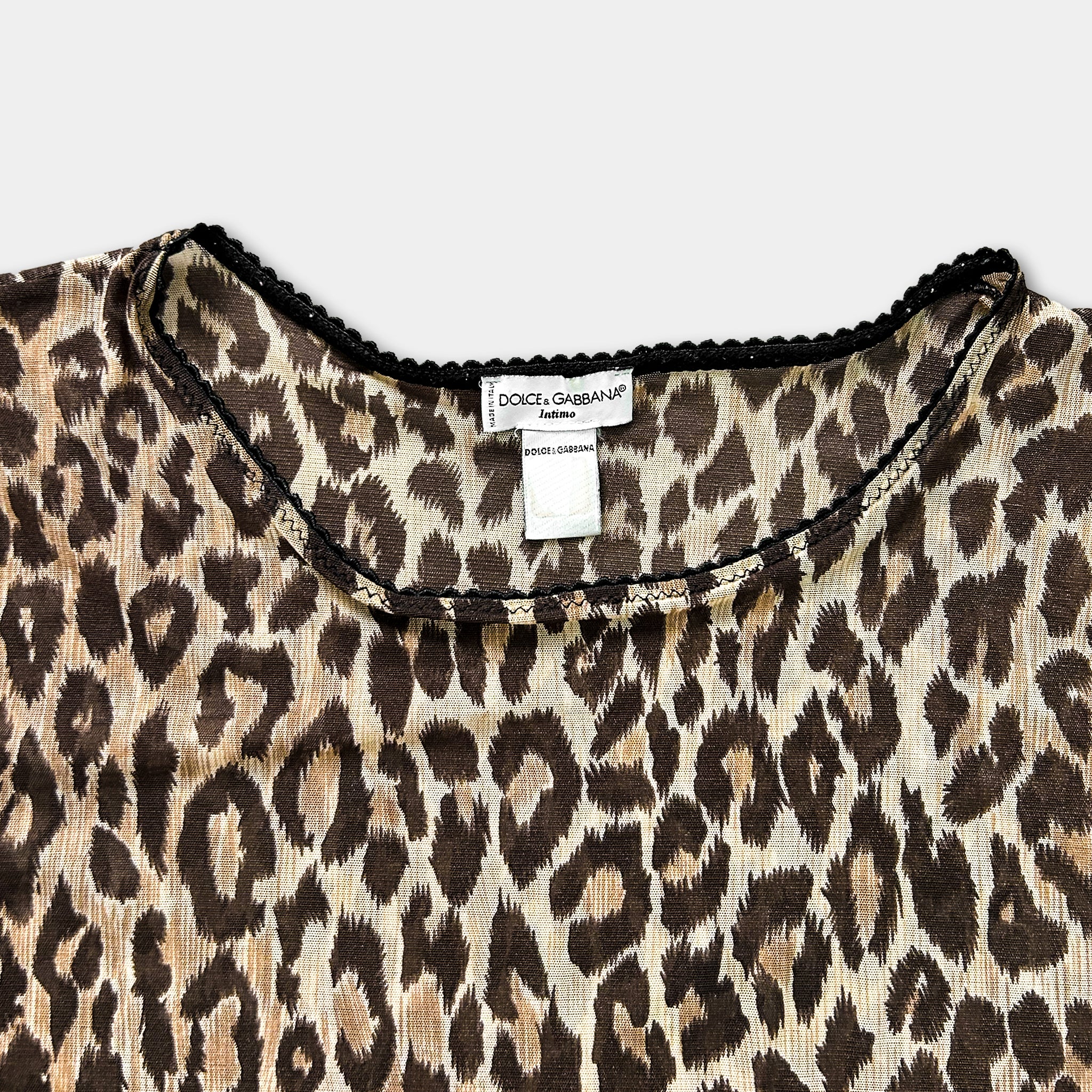 A close-up view of a leopard print top with a label on the collar.