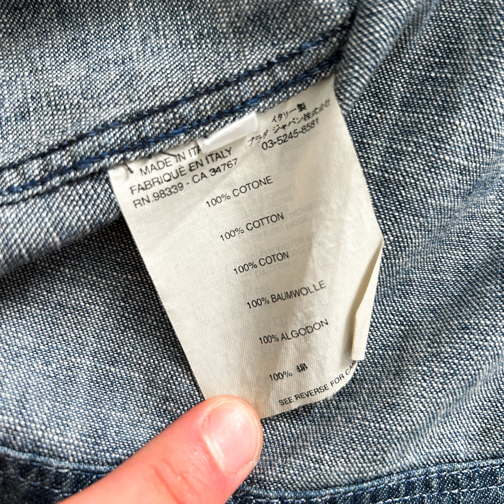A close-up view of a denim fabric label, showing details about the fabric, such as the brand, material, and production information.
