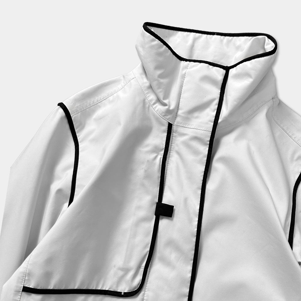 A close-up view of a white jacket with black trim, showing the collar, cuffs, and pockets.