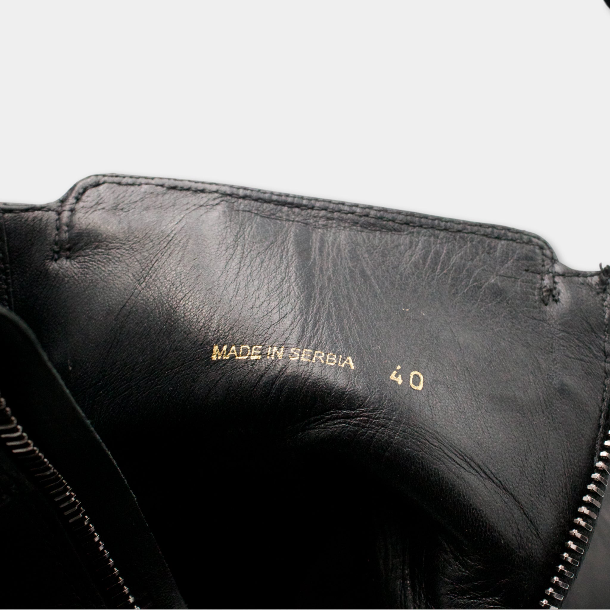 a close-up view of a black leather shoe, with the brand name "MADE IN SERBIA" printed on the sole.