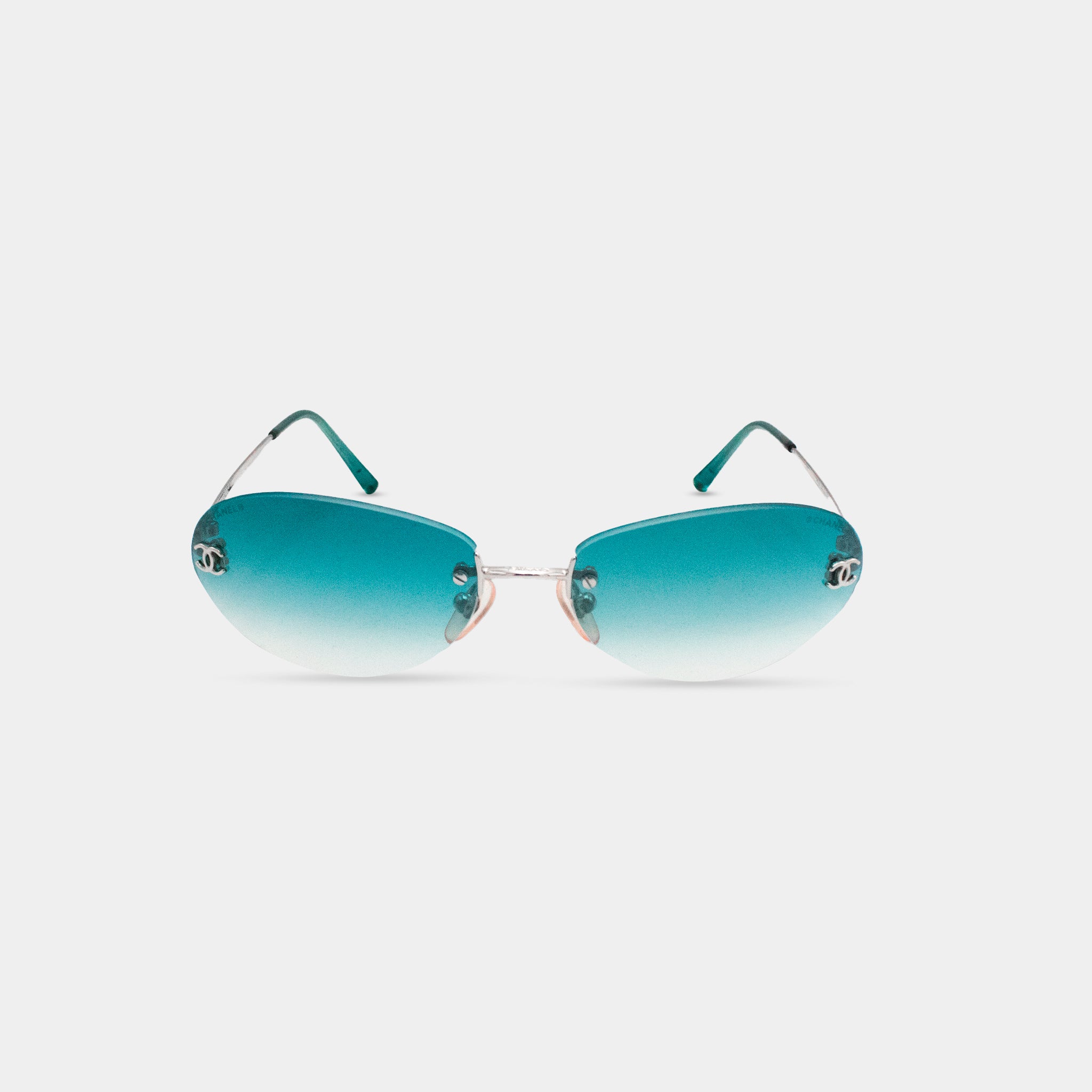 A pair of teal-colored sunglasses with a Chan logo on the temples.