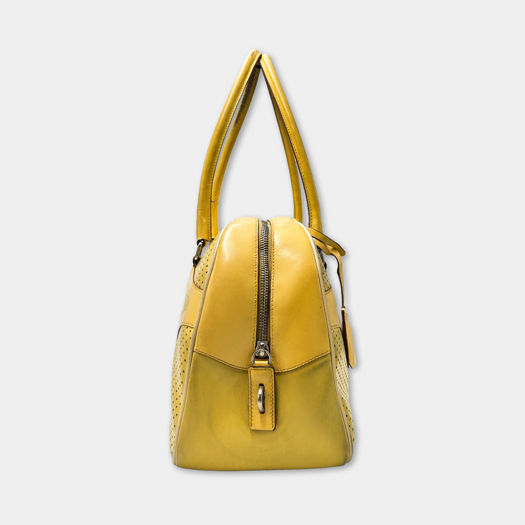 A yellow leather handbag with a zipper closure and two handles.