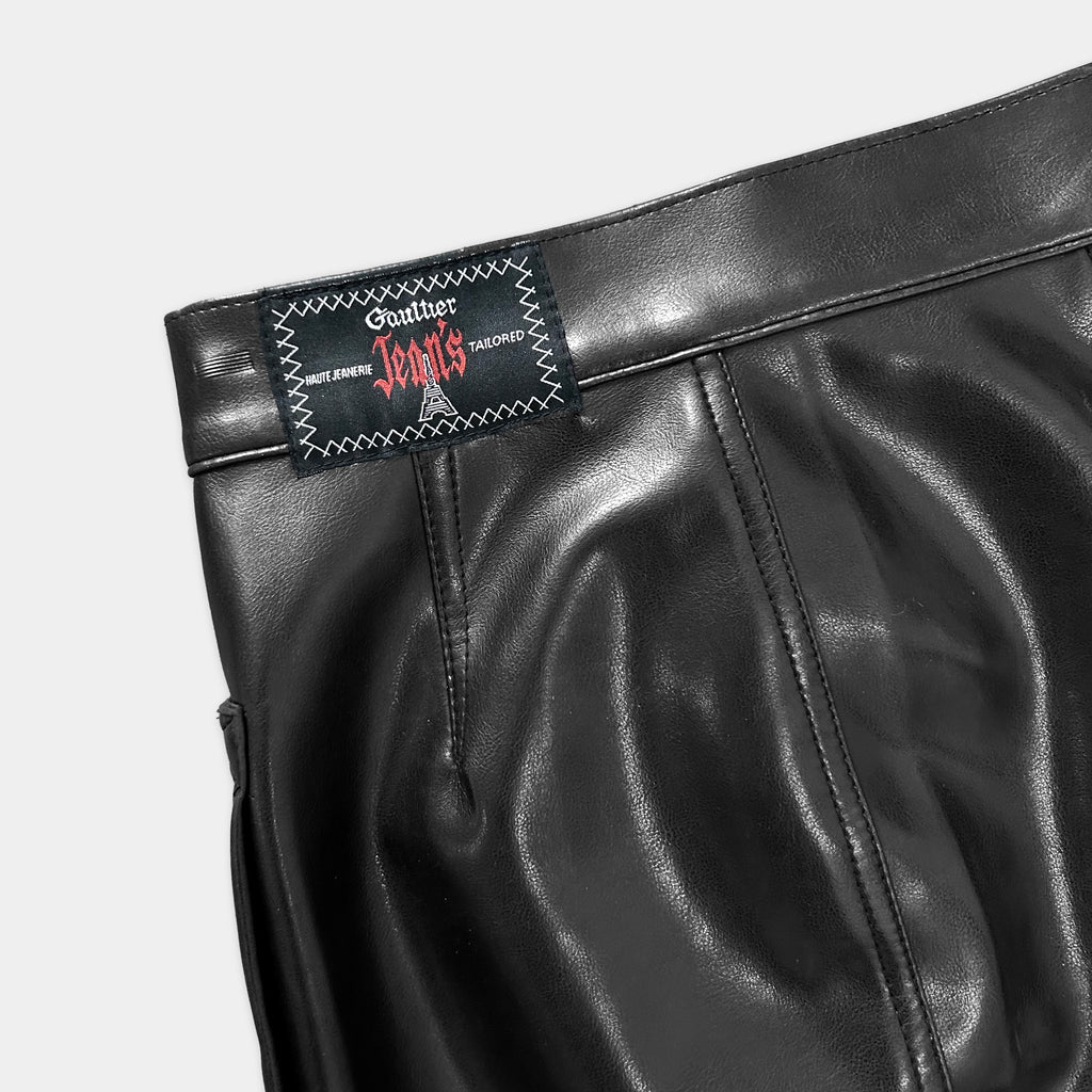 A close-up view of a black leather skirt or trouser with a label or tag attached to it.