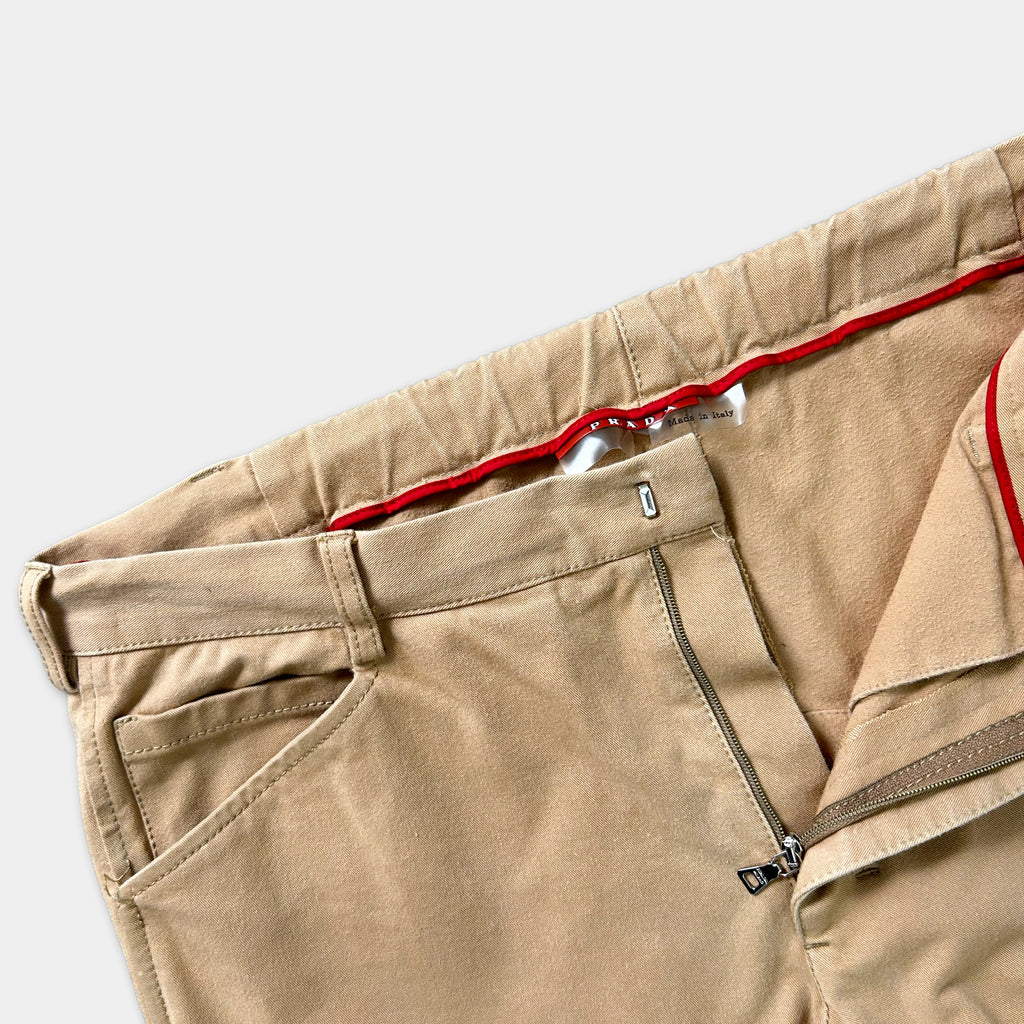 A pair of khaki pants with a red zipper detail.