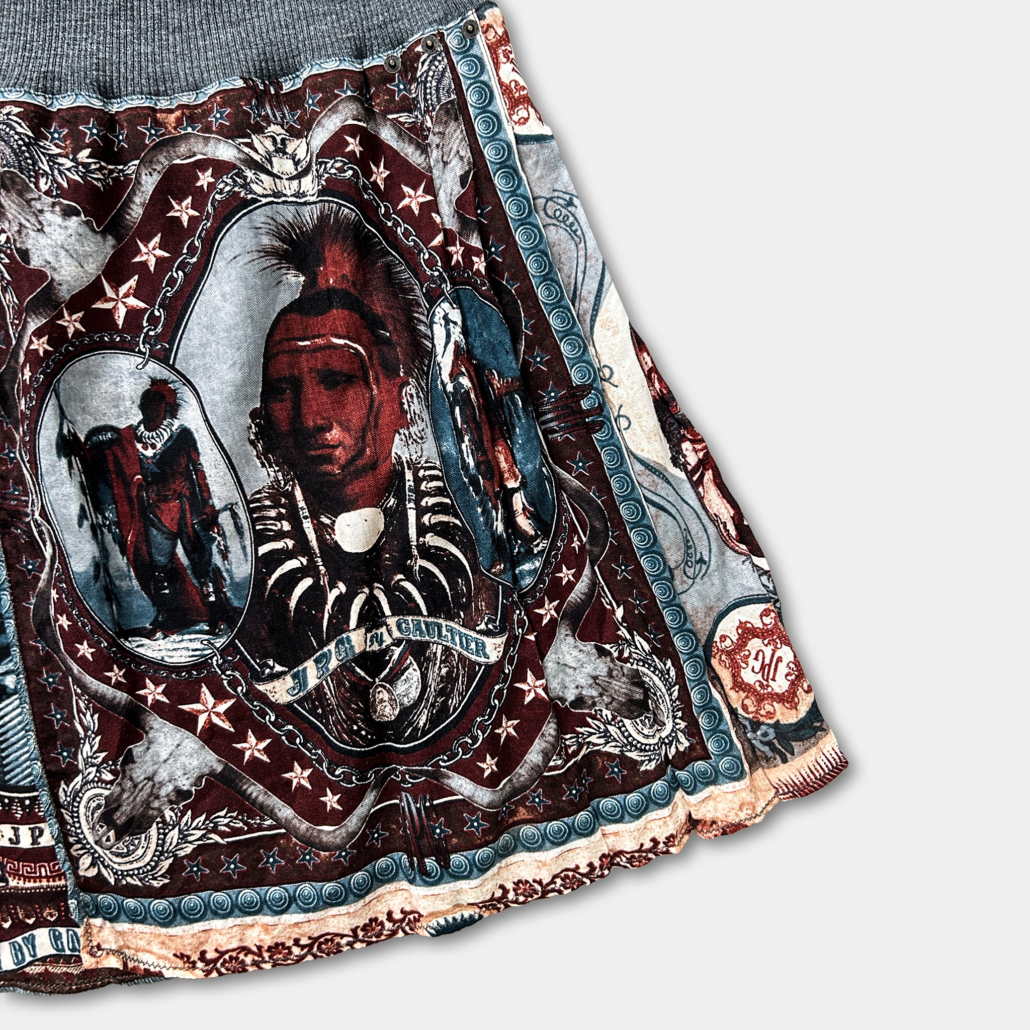 a skirt with a colorful, intricate design. The design includes a central image of a person with a distinctive hairstyle, surrounded by various decorative elements and patterns.