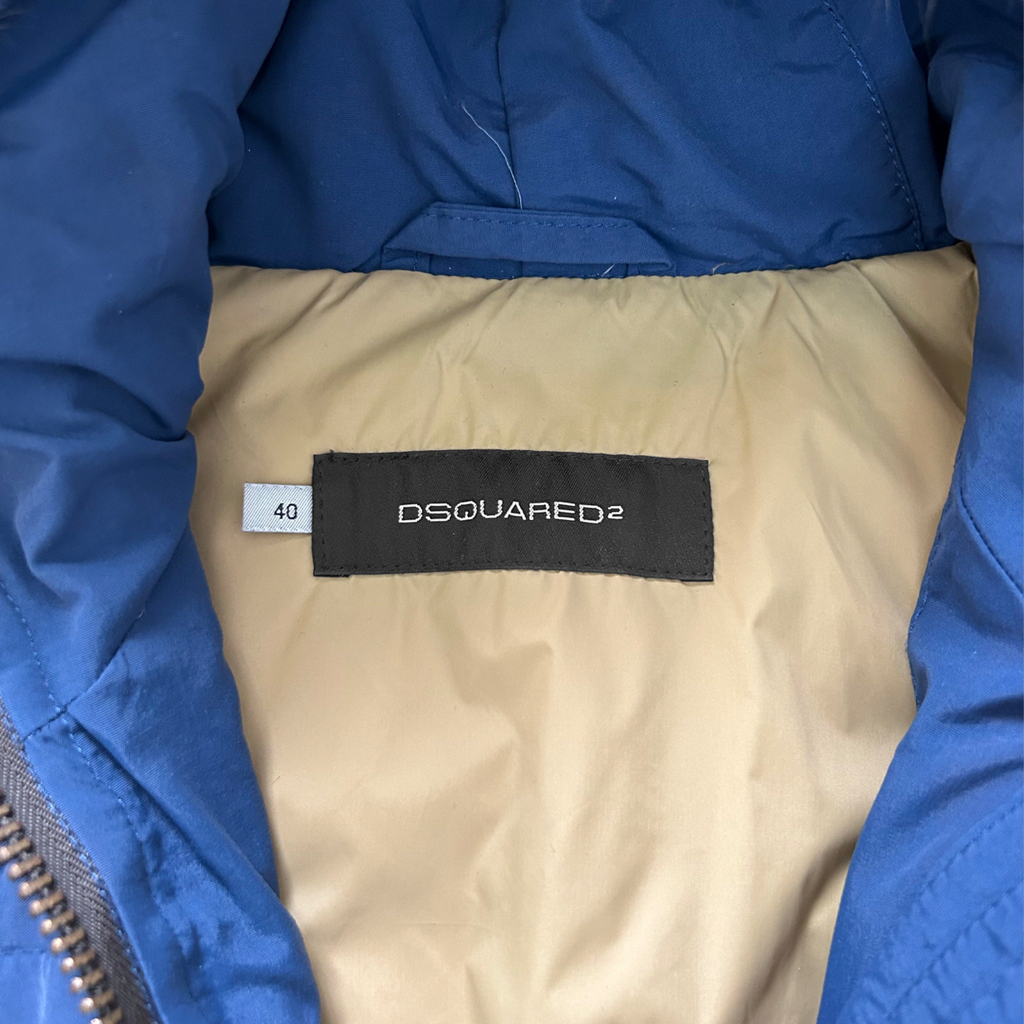 a close-up view of a blue and beige jacket with a label on the back, displaying the brand name "DSQUARED".