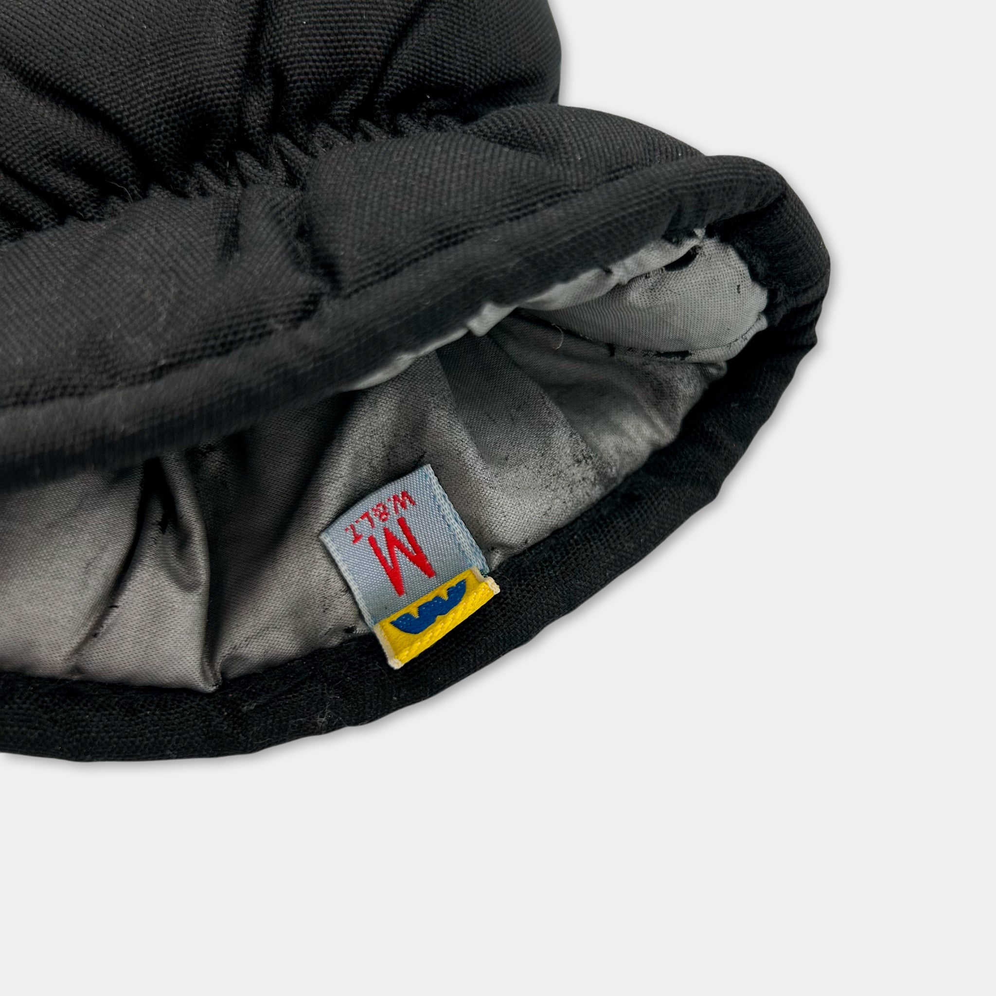 A close-up view of a black and gray fabric item, possibly a hat or glove, with a label attached to it.