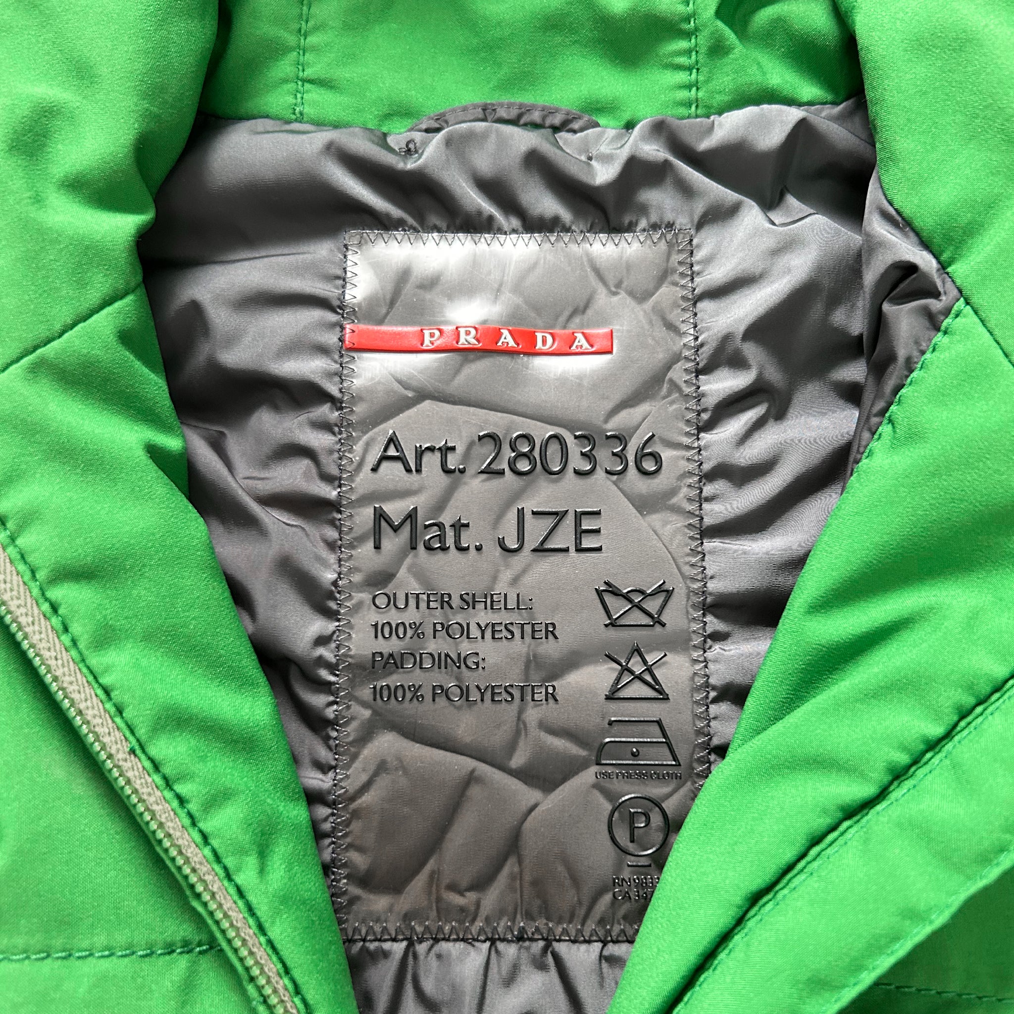 a close-up view of a green jacket with a label on the back, indicating the material and care instructions.