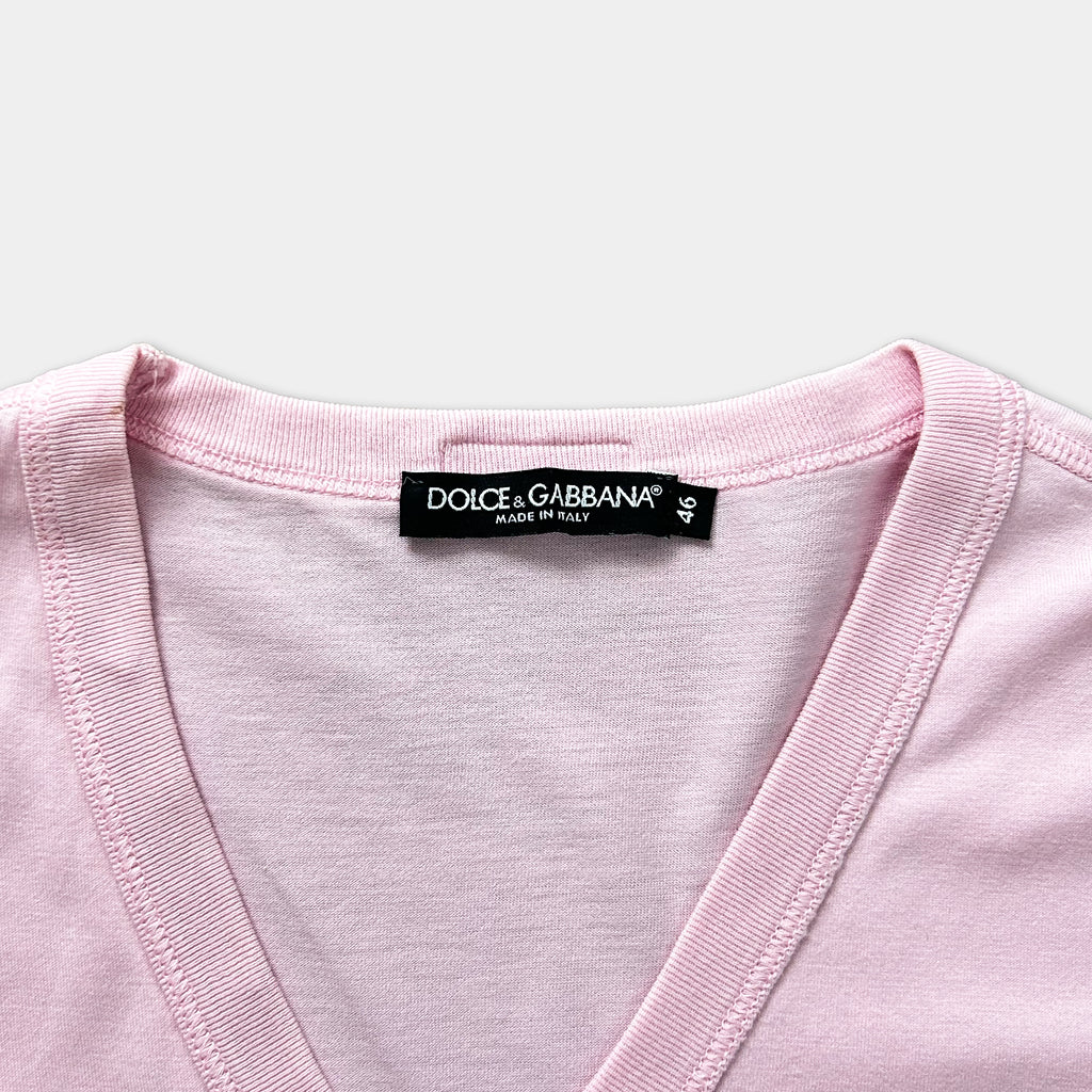 A close-up view of a pink v-neck t-shirt with a label on the collar.