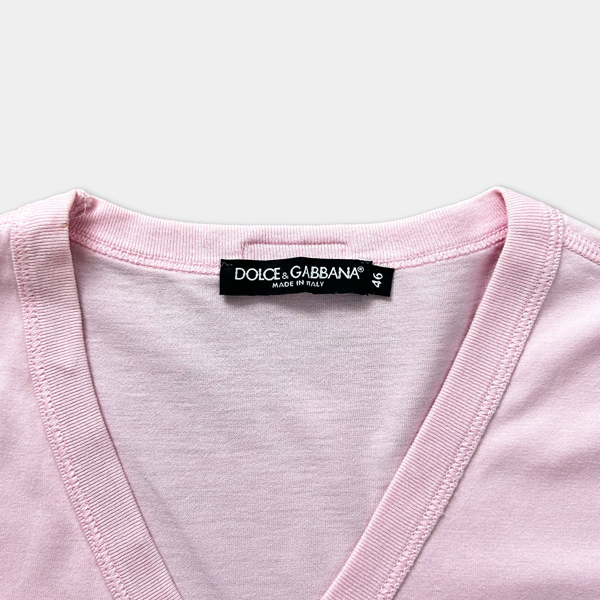 A close-up view of a pink v-neck t-shirt with a label on the collar.