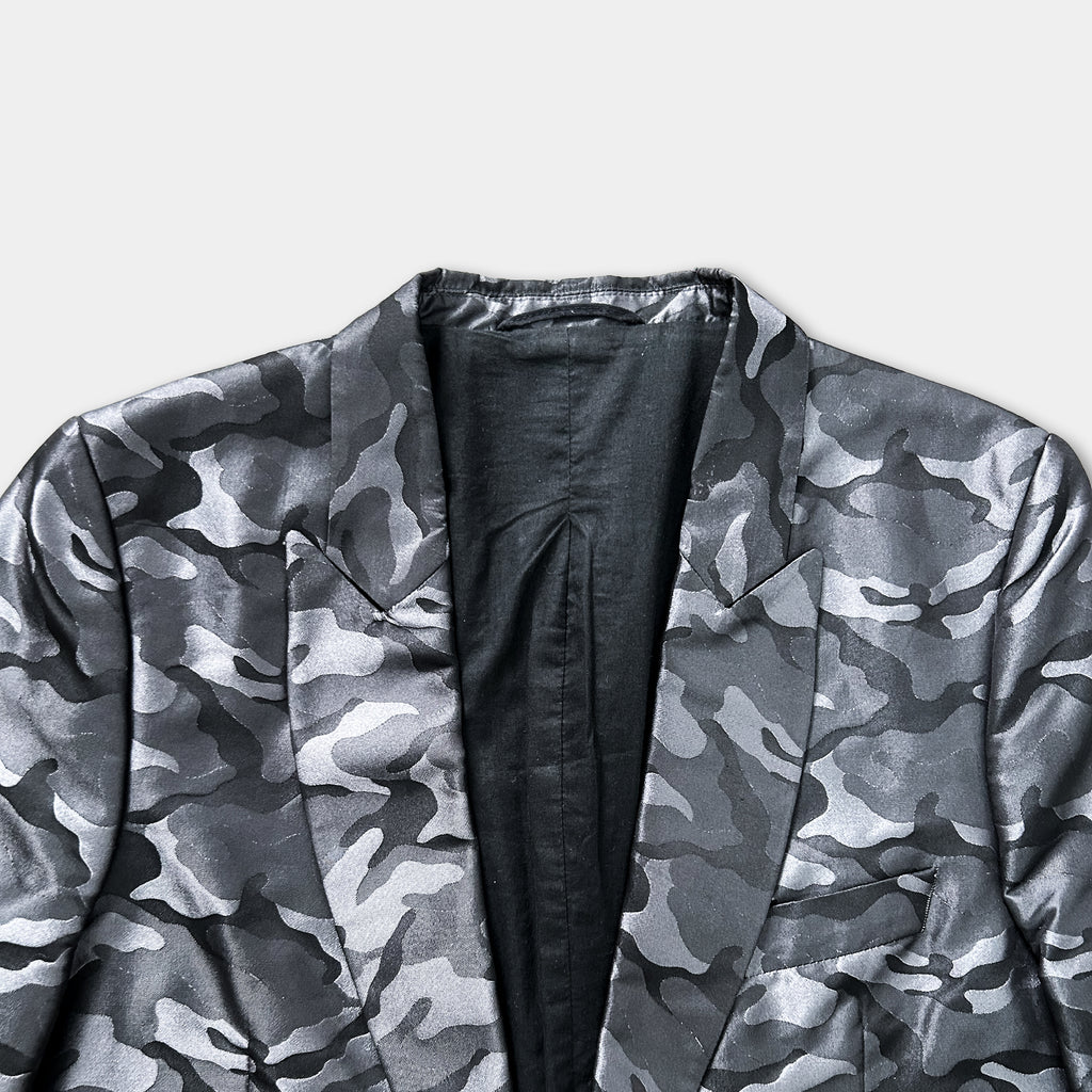 A close-up view of a black and grey camouflage jacket with a collar and lapel.