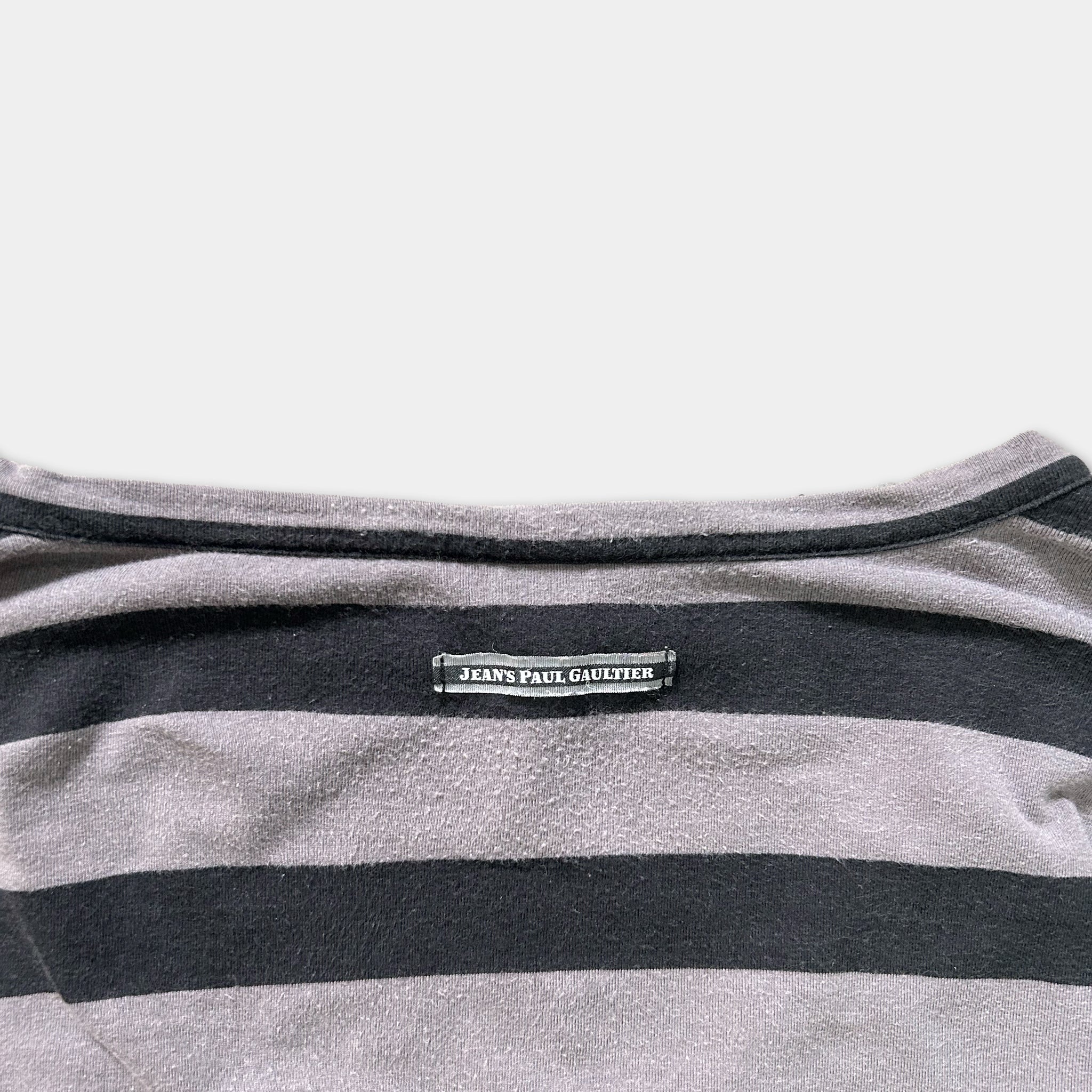 a close-up view of a gray and black striped shirt with a label on the back.