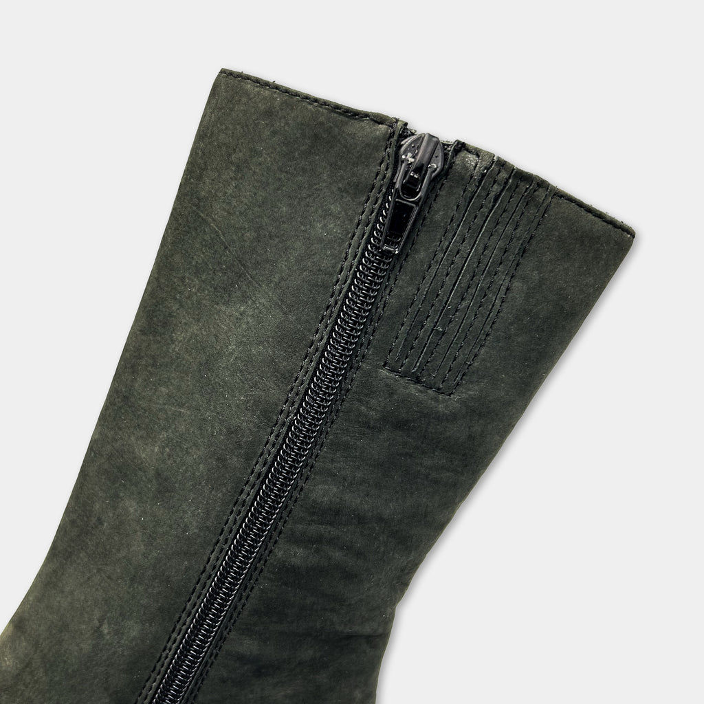 A close-up view of a dark green suede boot with a zipper on the side.