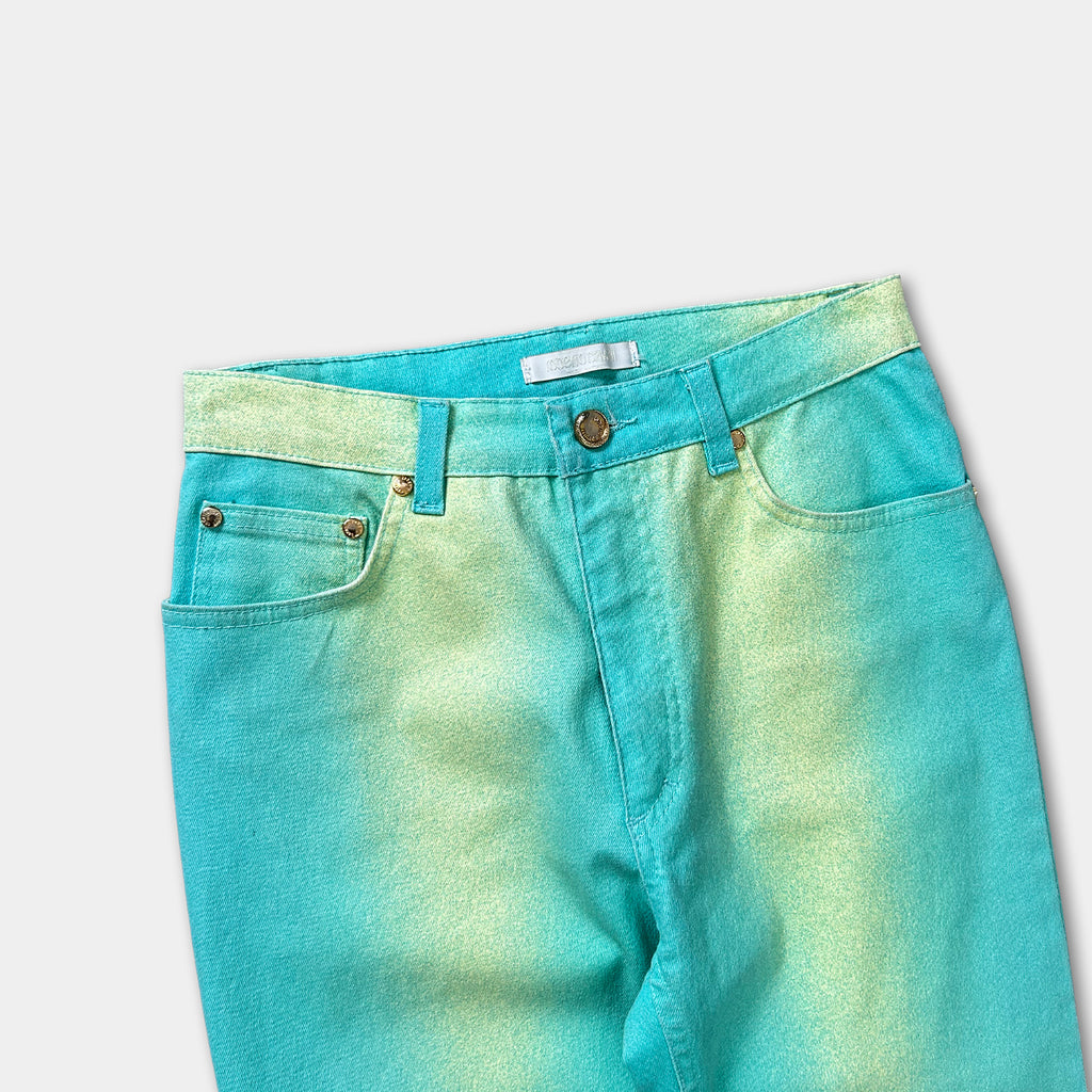 A pair of turquoise-colored jeans with a gold-colored belt buckle.