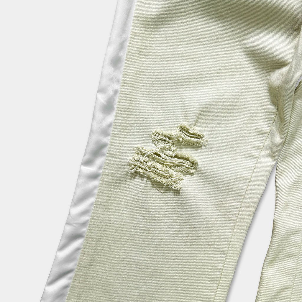 A close-up view of a pair of white pants with a noticeable tear in the fabric.