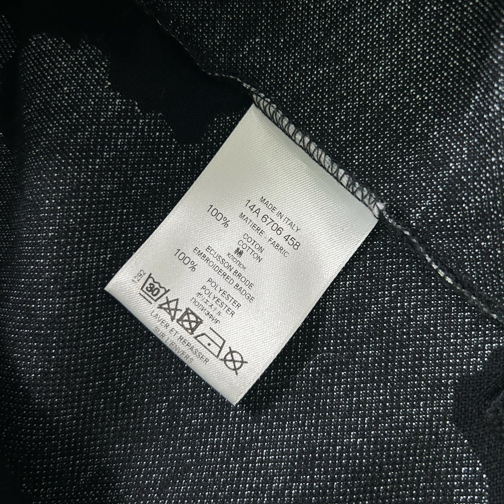 a close-up view of a white label with black text and symbols, placed on a dark fabric surface.