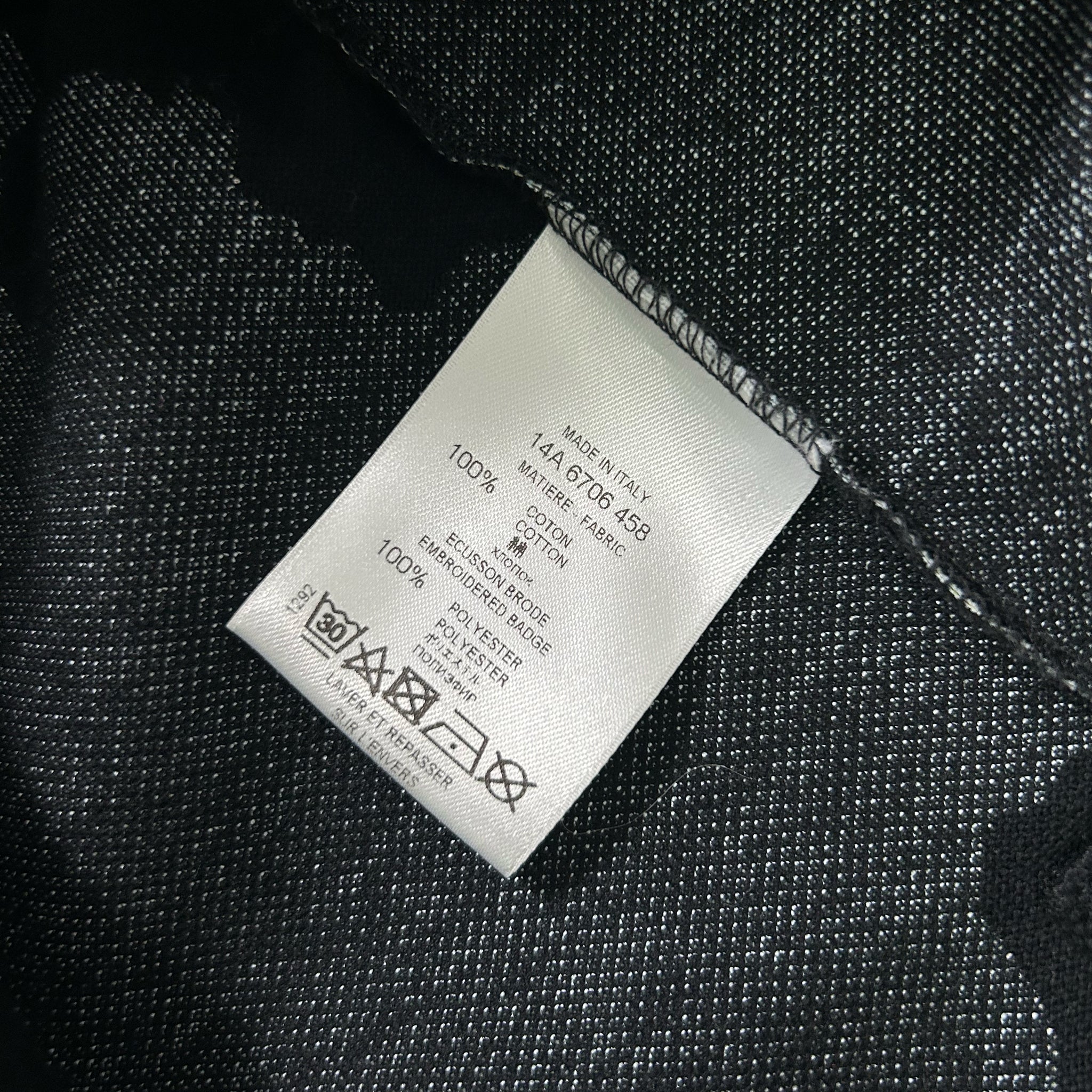a close-up view of a white label with black text and symbols, placed on a dark fabric surface.