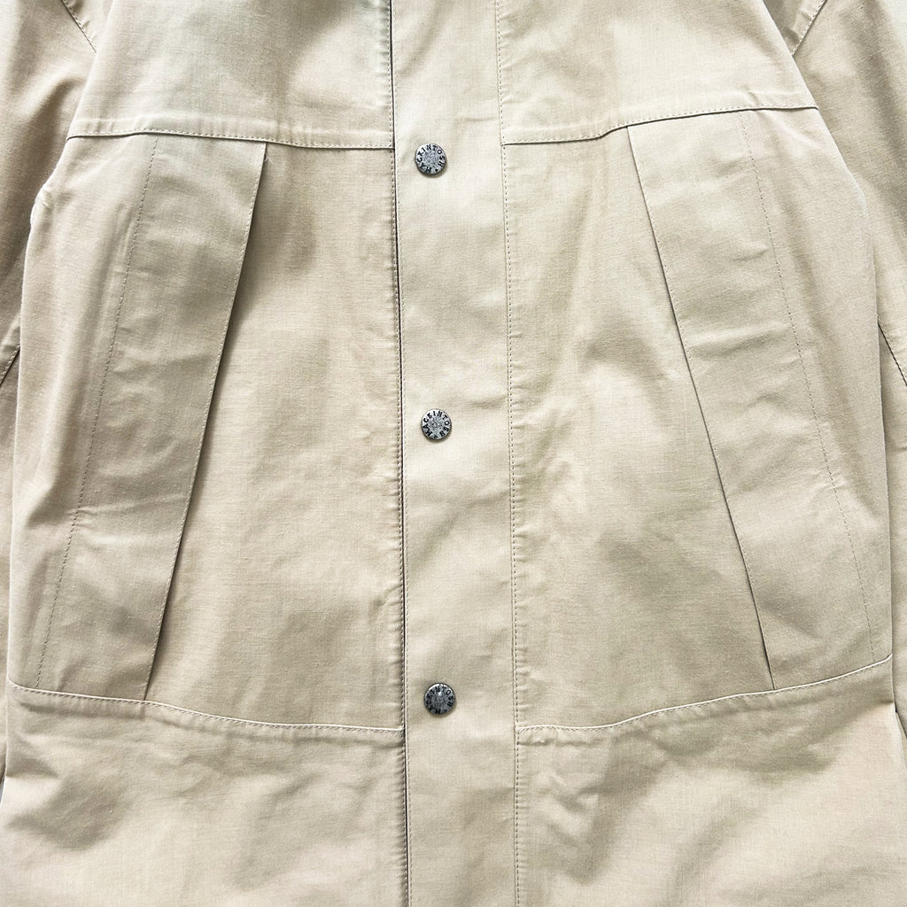 a close-up view of a beige jacket with three buttons and two pockets.