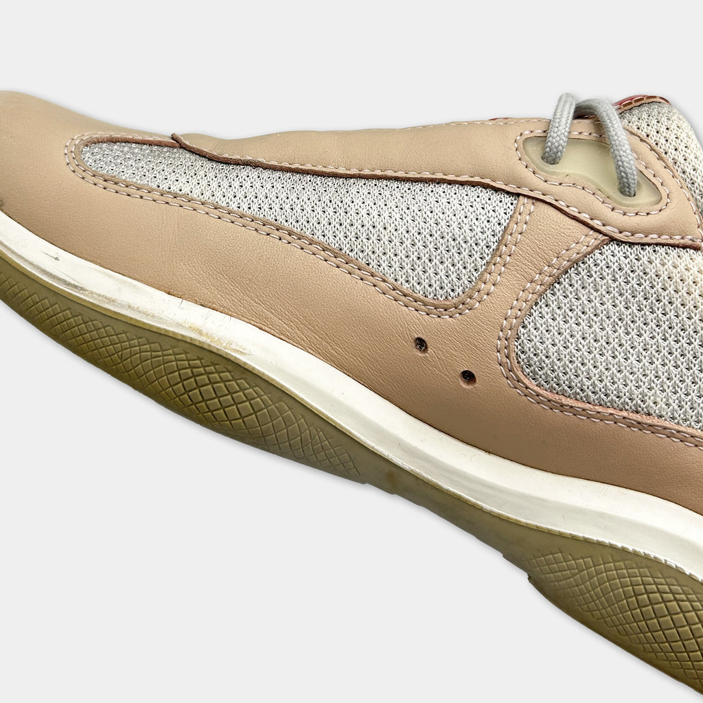 A close-up view of a tan and white athletic shoe with a mesh panel on the side.