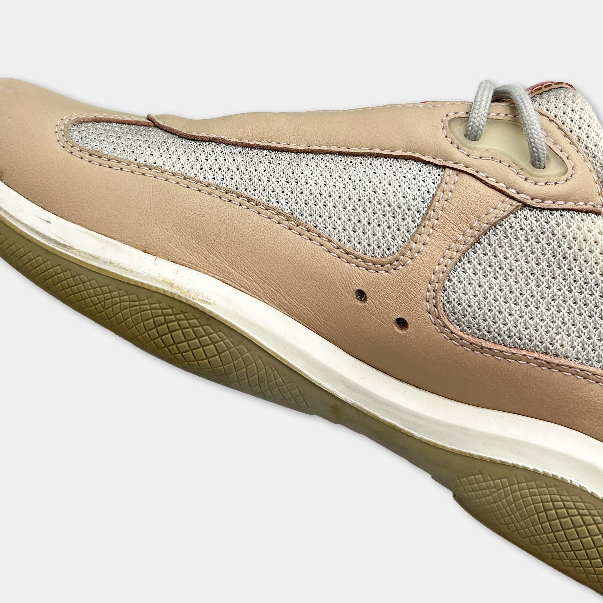 A close-up view of a tan and white athletic shoe with a mesh panel on the side.