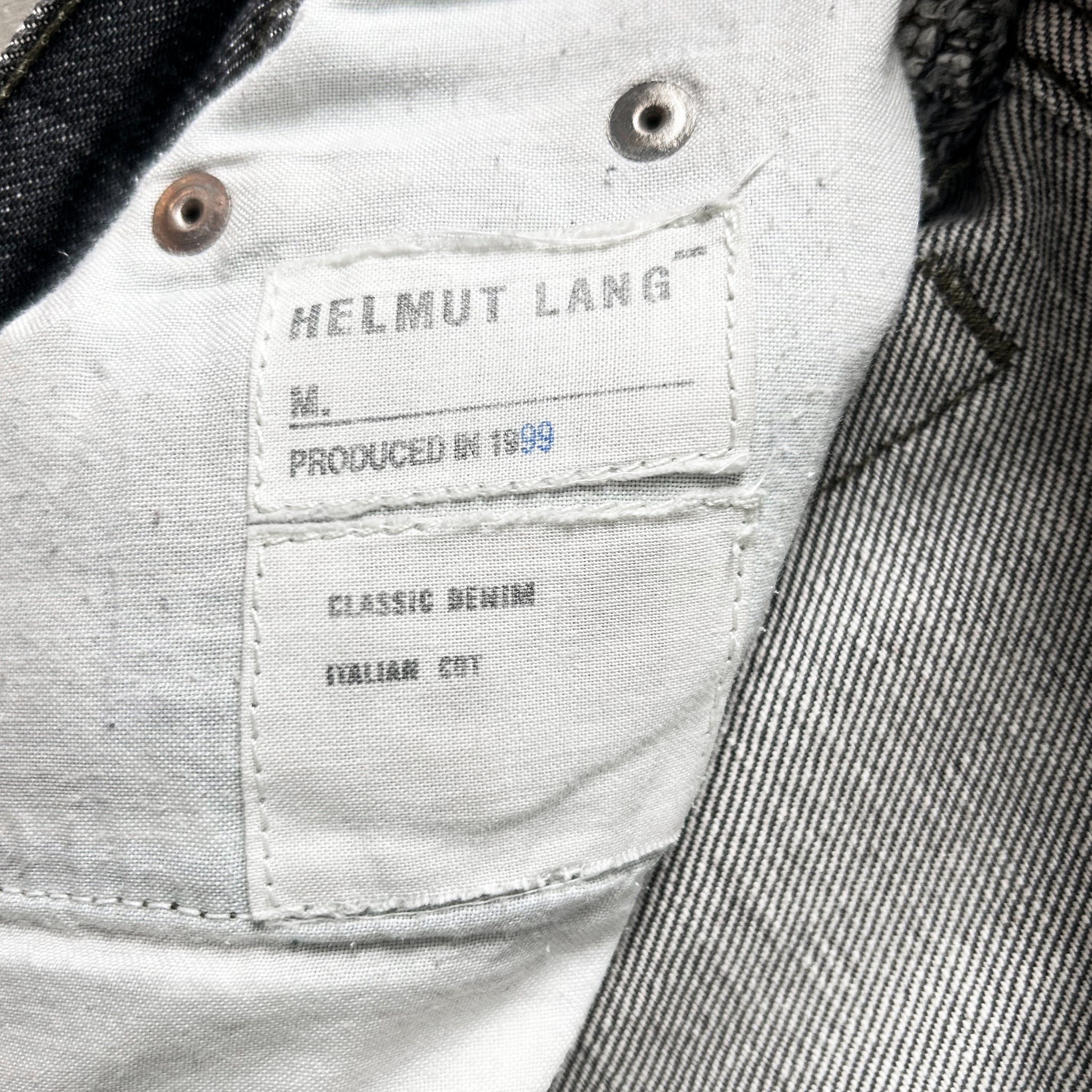 a close-up view of a label on a piece of clothing, specifically a pair of jeans. The label is white and has text and numbers printed on it.