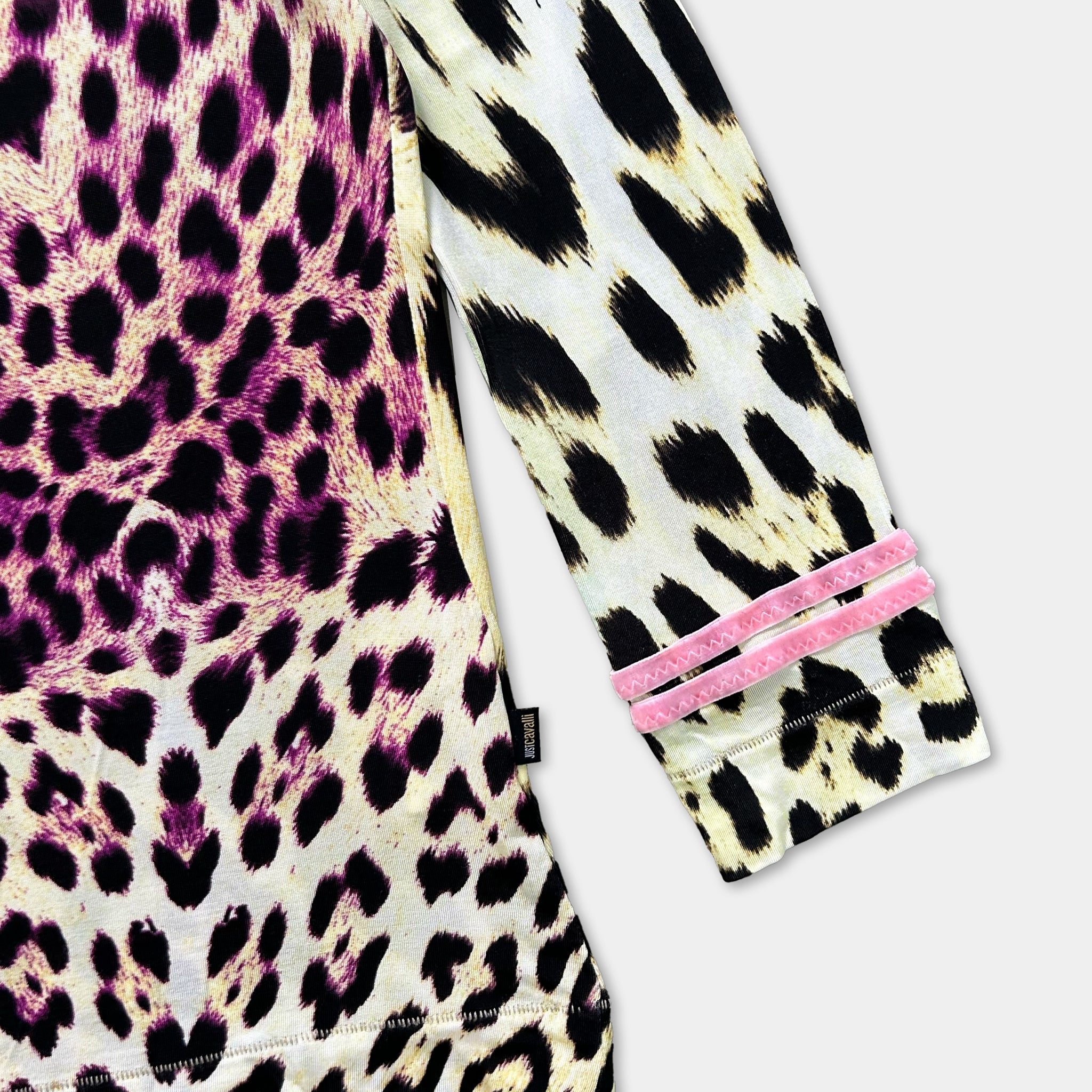 a close-up view of a long-sleeved shirt with a leopard print pattern. The shirt has a pink and white color scheme, and the sleeves are adorned with pink velvet straps.