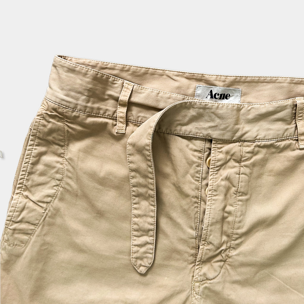 A pair of khaki cargo shorts with a belt and a label on the waistband.